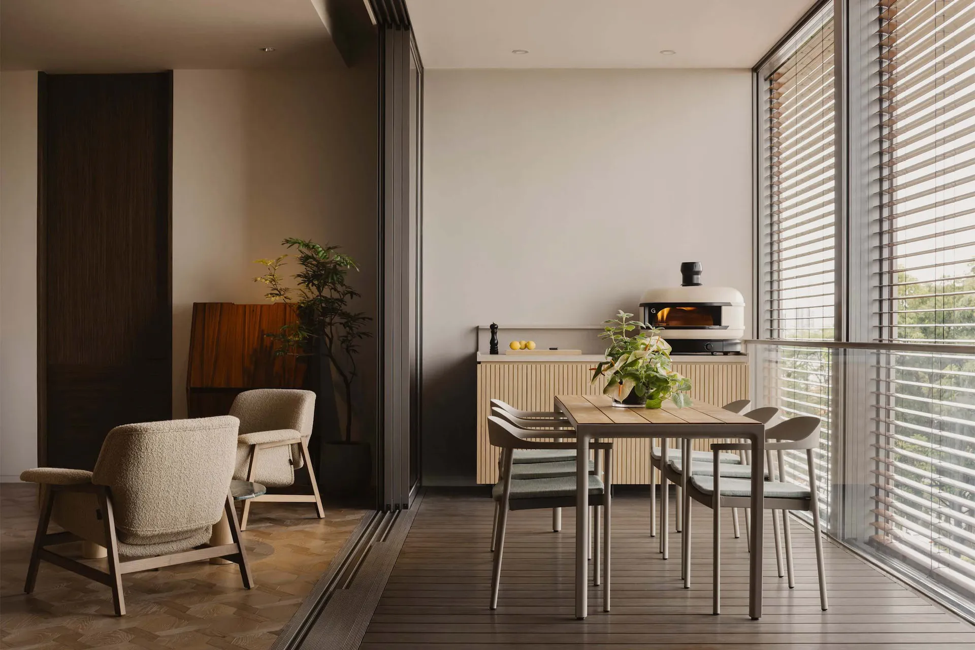 Modern minimalist kitchen with wood and metal elements and a plant on a table.