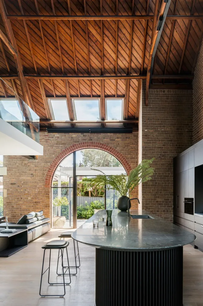 Industrial-style kitchen with brick walls, wooden beams, and concrete countertops.
