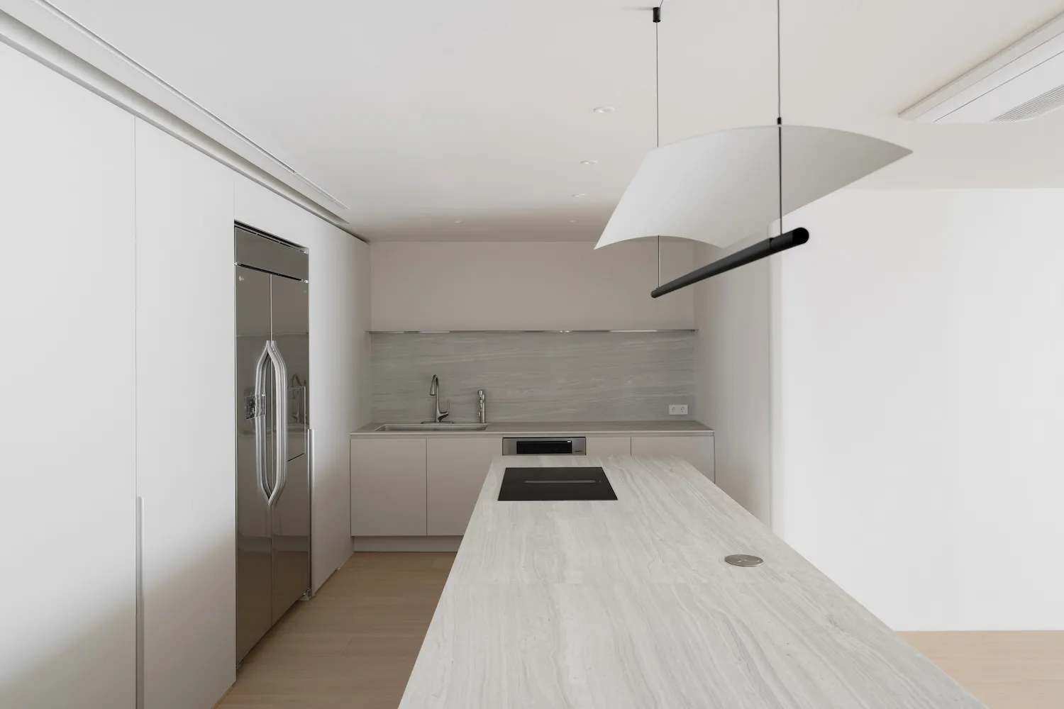 Modern minimalist kitchen interior with white cabinetry and marble countertops.