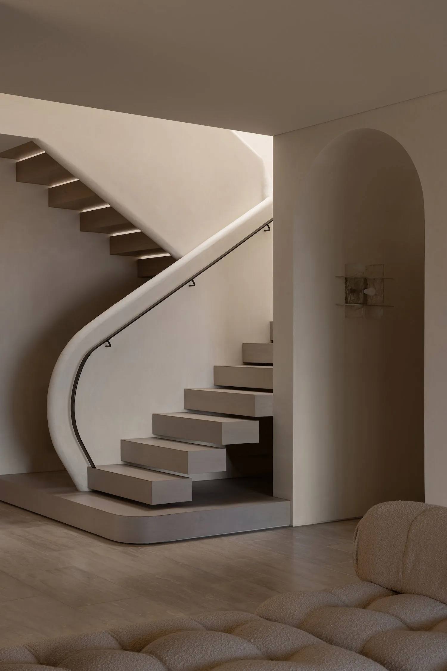 A minimalist staircase with wooden steps and a concrete wall, featuring a modern railing and a well-lit space.