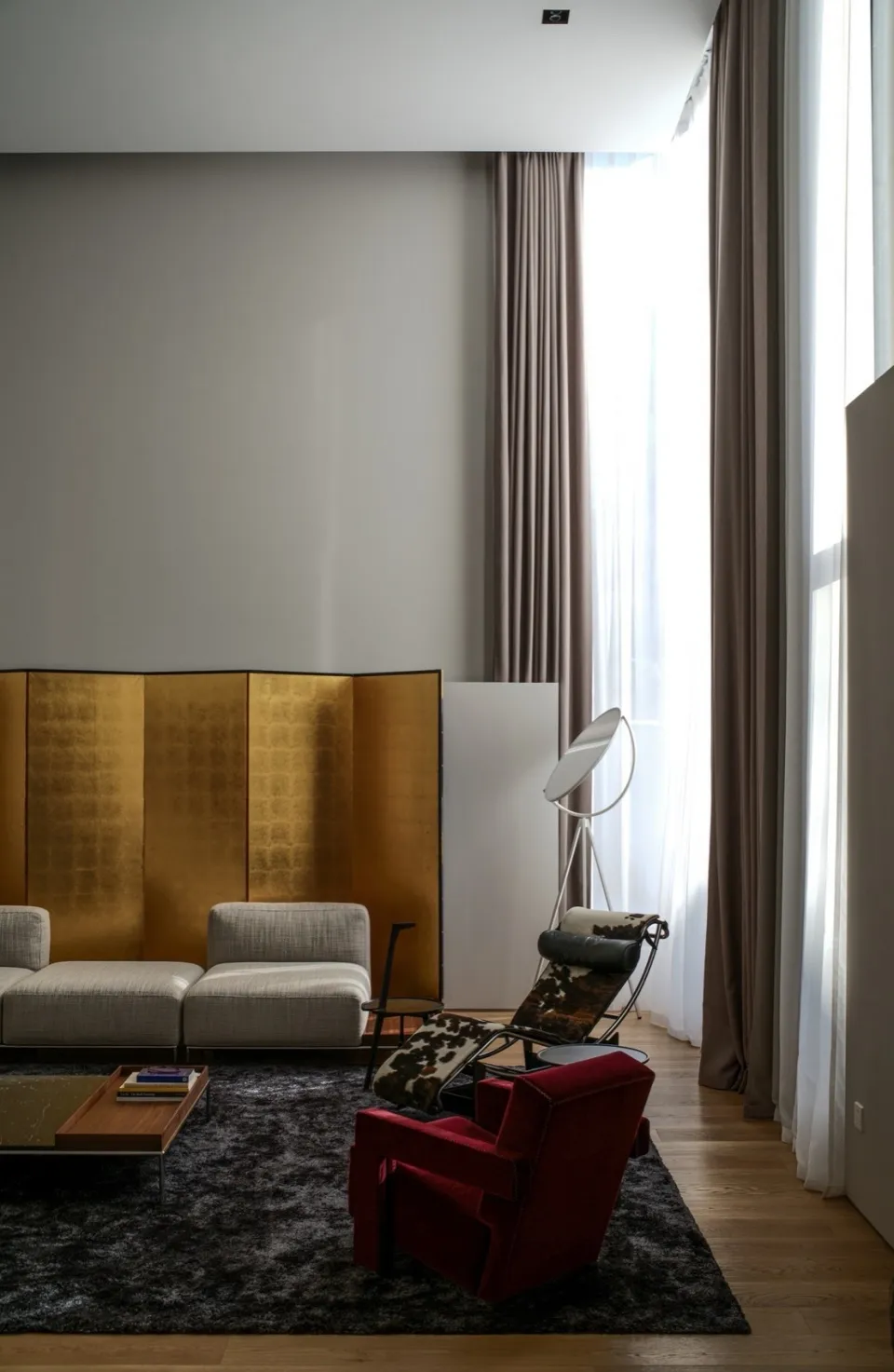 A modern living room featuring textured fabric furniture, concrete flooring, and leather accents.