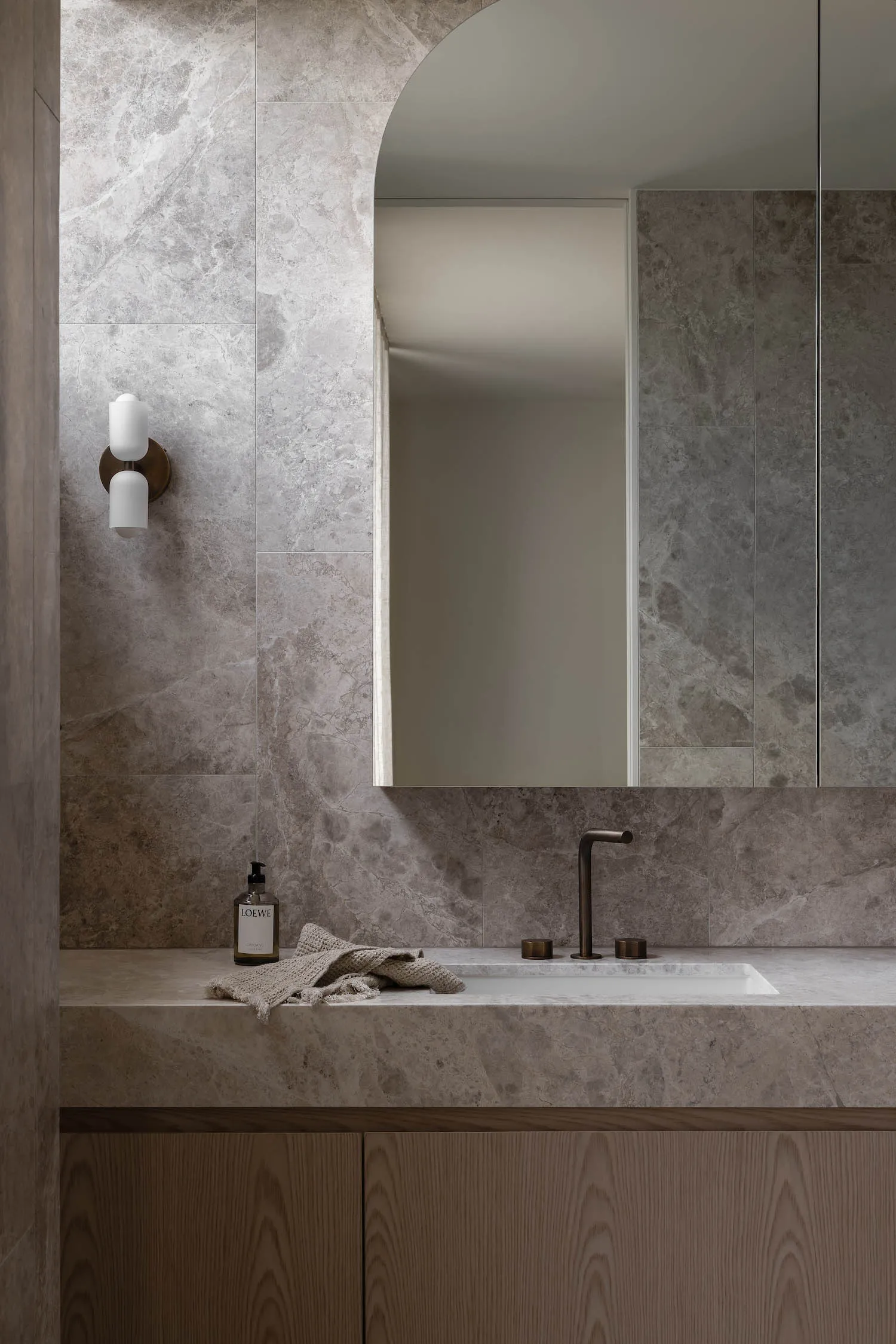 Modern bathroom with marble walls and floor, featuring a sleek countertop and minimalist design.