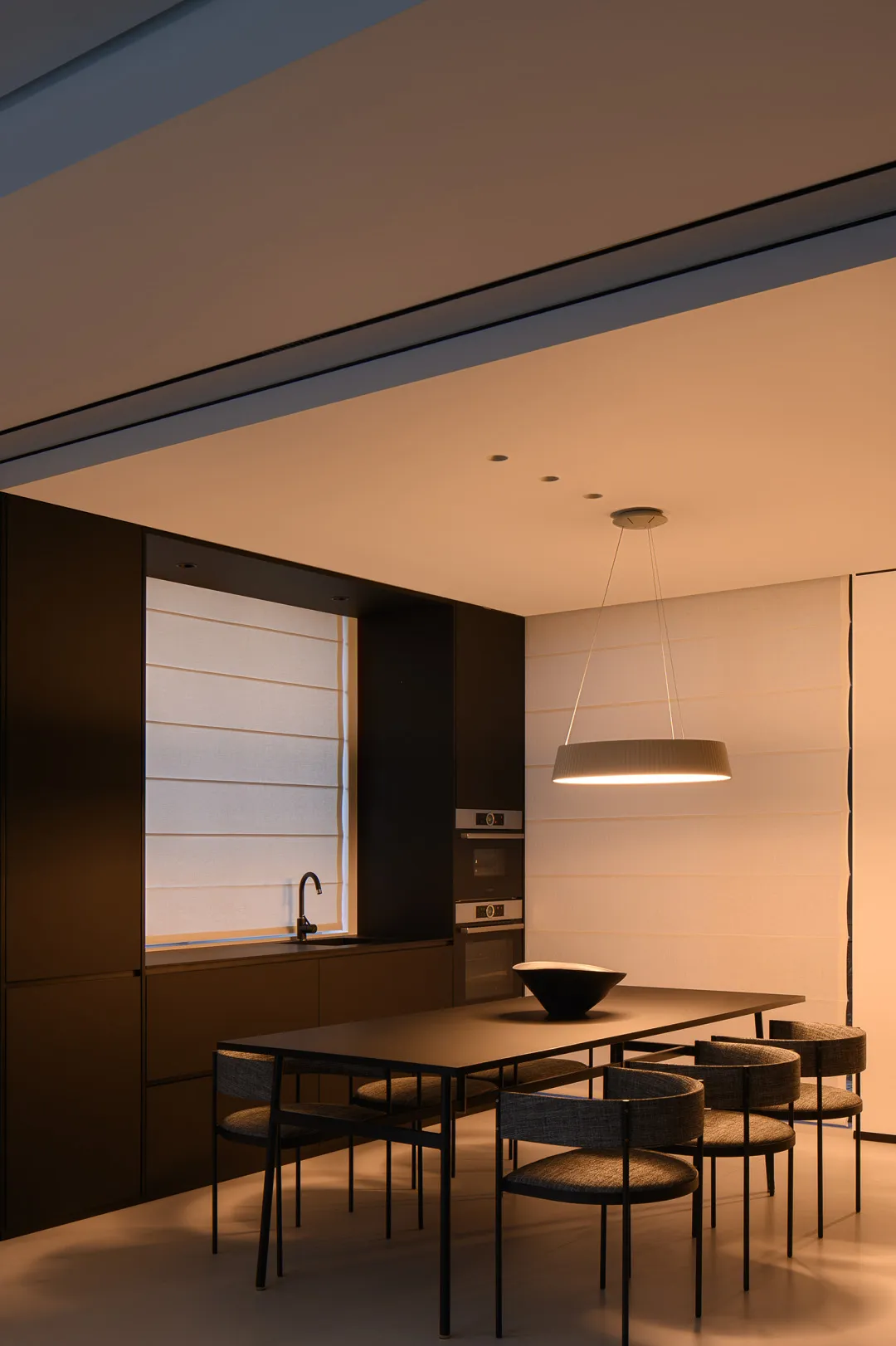 Modern minimalist kitchen with walnut cabinetry, metal accents, and fabric upholstered chairs.