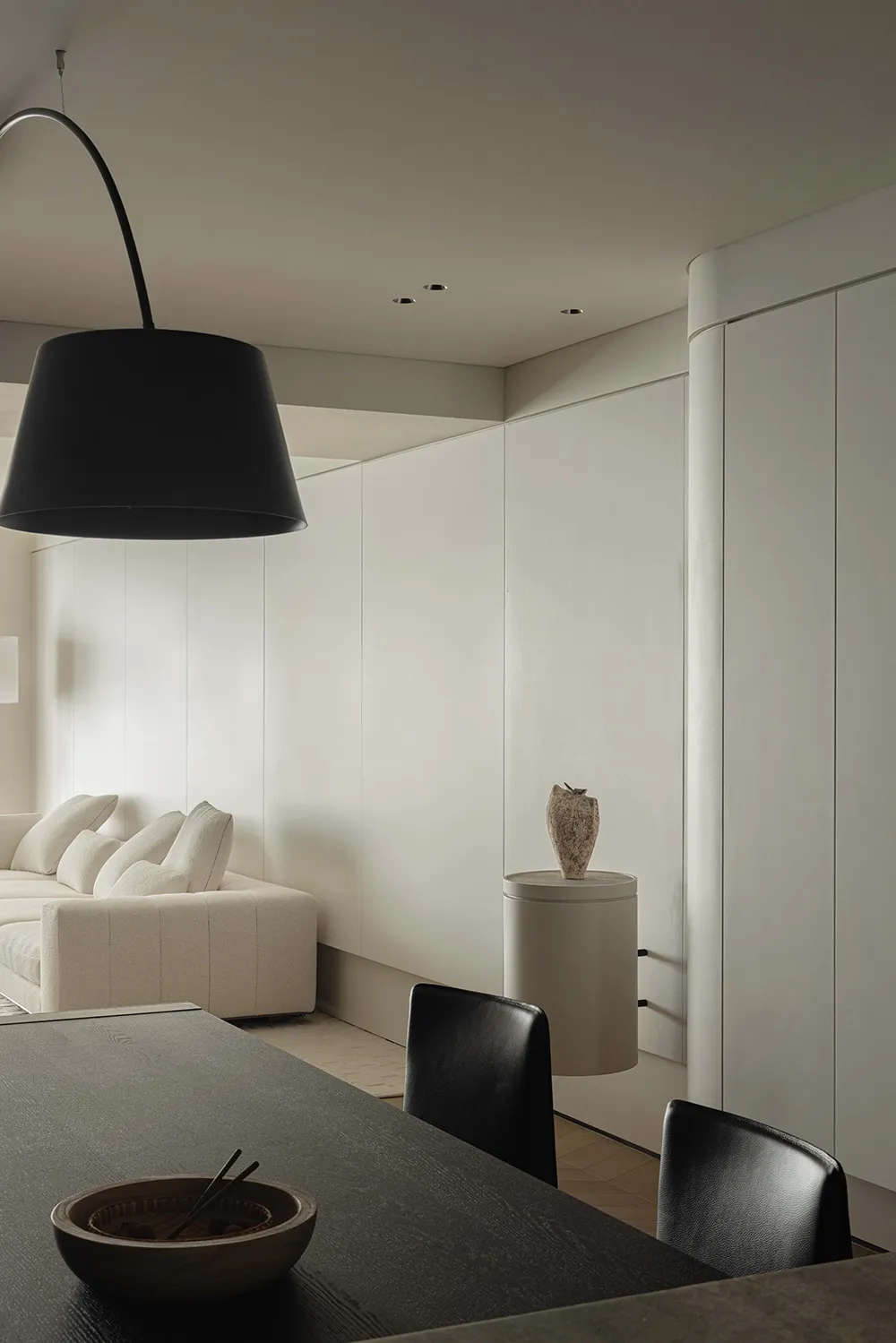 A minimalist dining room features white cabinets and black furniture, creating a modern and sleek ambiance.