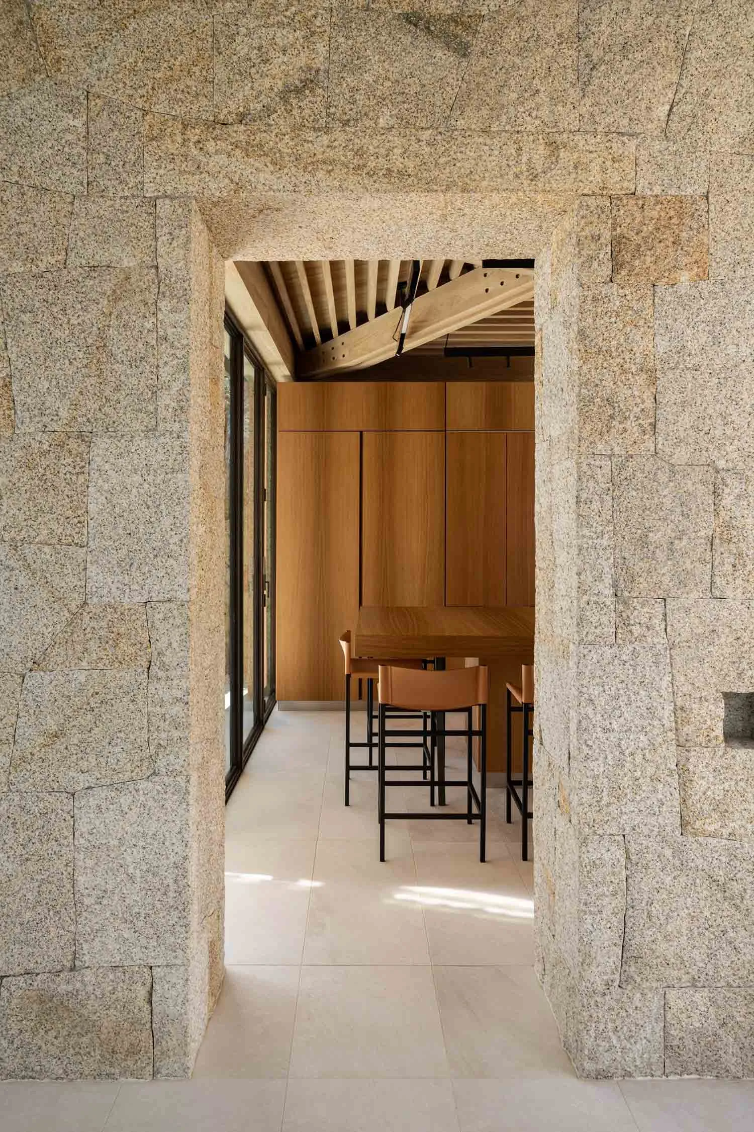 Modern kitchen with minimalist design featuring natural stone flooring and walls