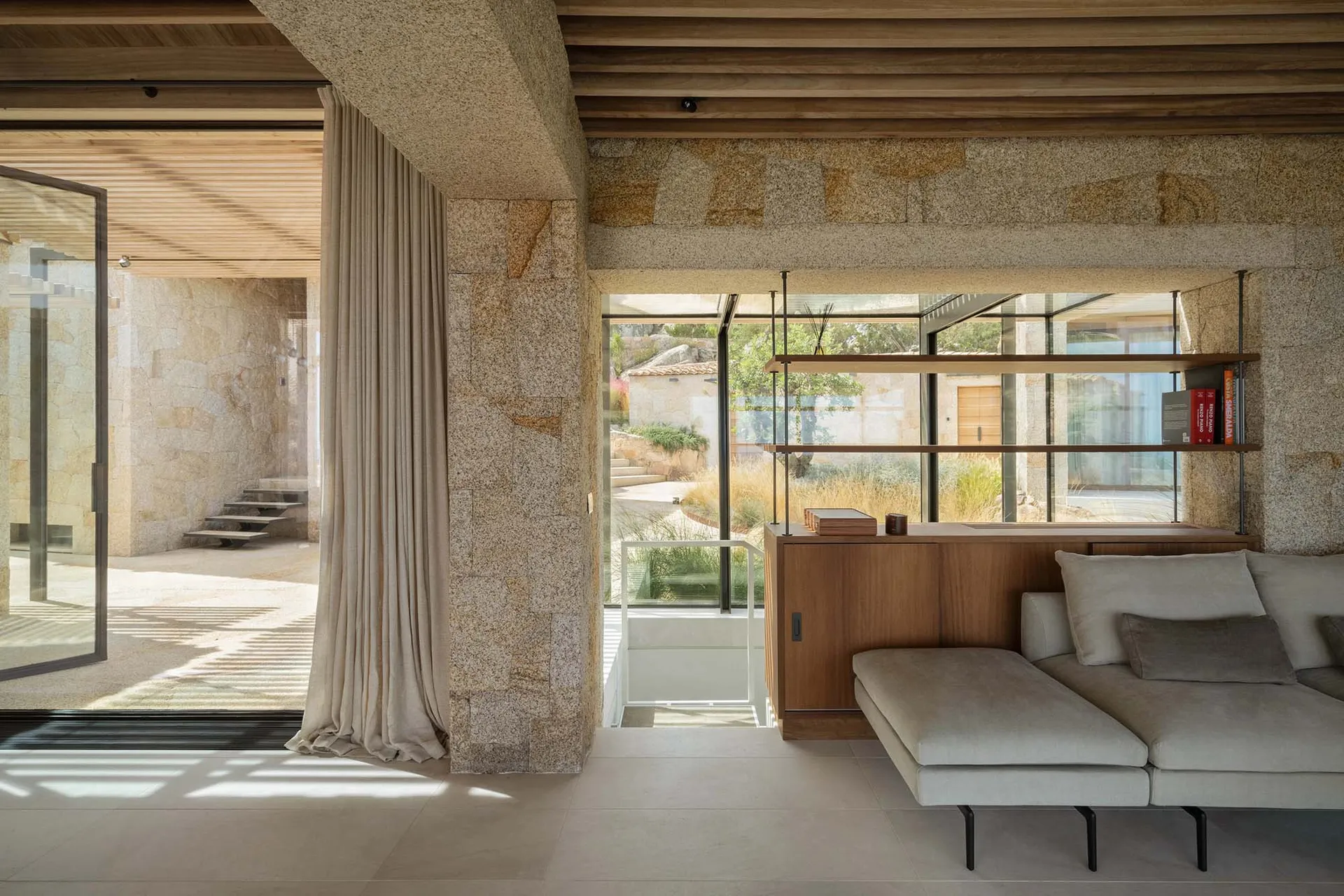 Modern living room with concrete walls and floor, featuring a comfortable sofa and bookshelf.