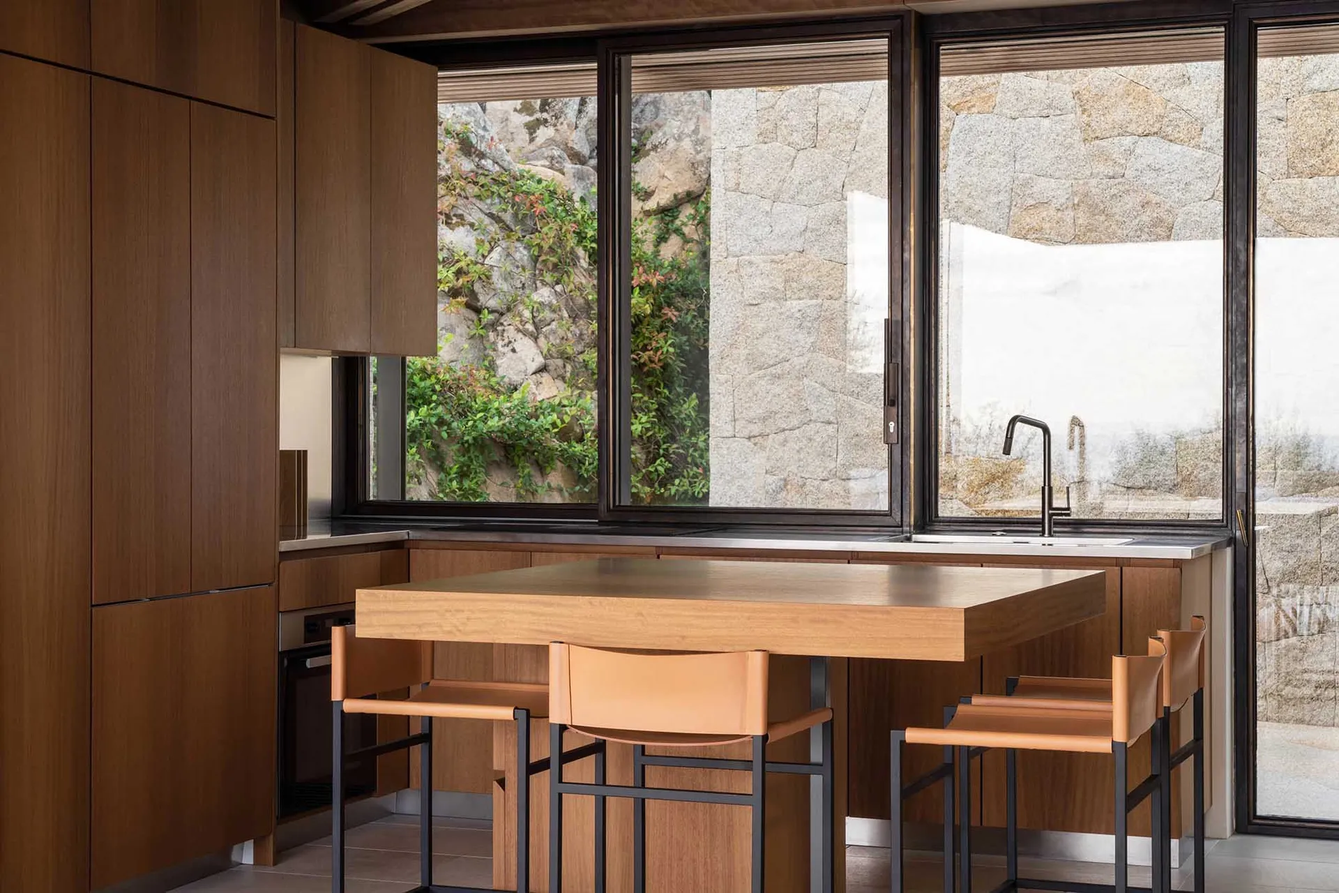 A modern kitchen featuring wooden cabinets and metal chairs.