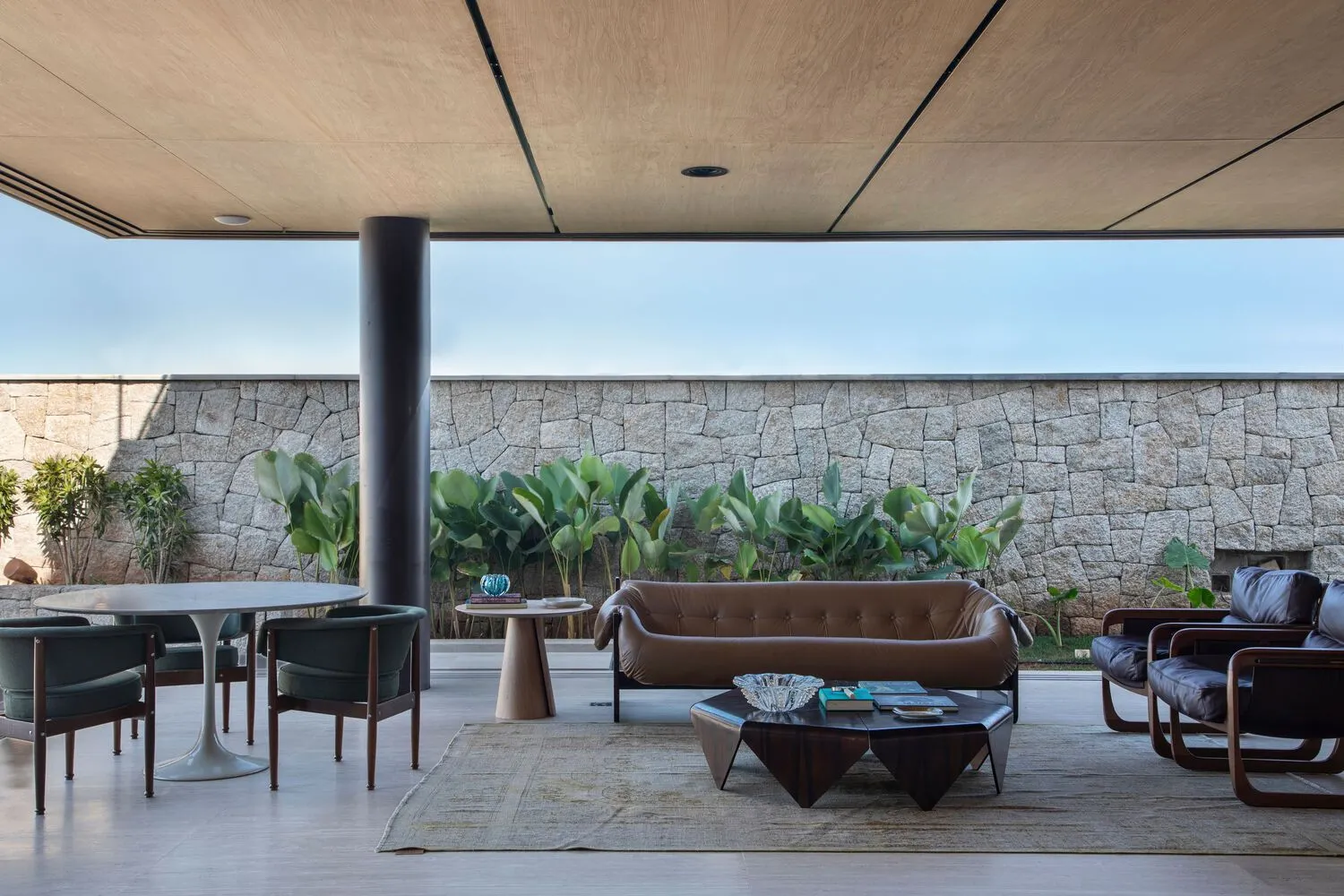 Modern living room with wooden ceiling, concrete walls, and leather furniture.