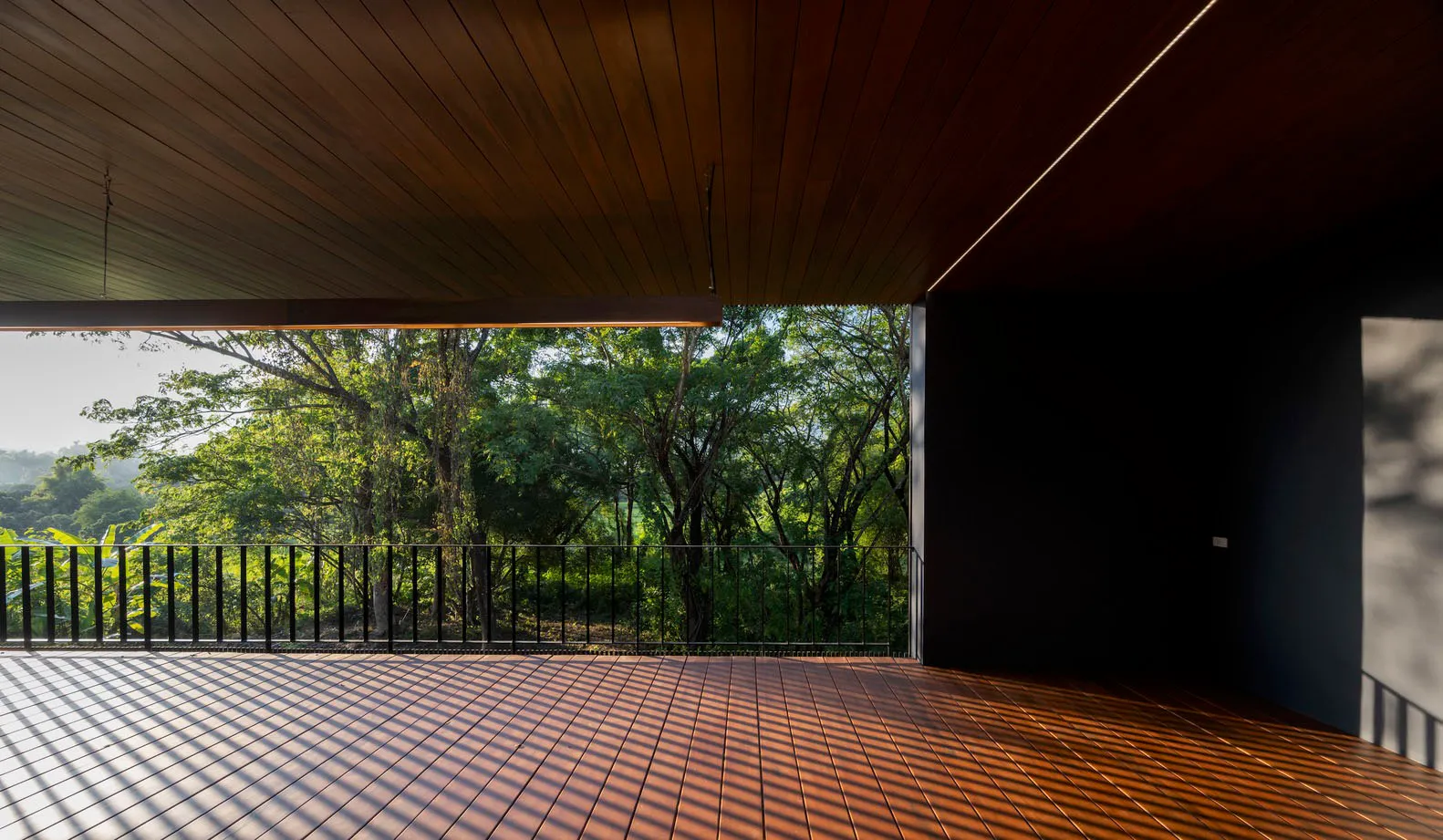 Modern interior space featuring wooden flooring and glass windows overlooking greenery.
