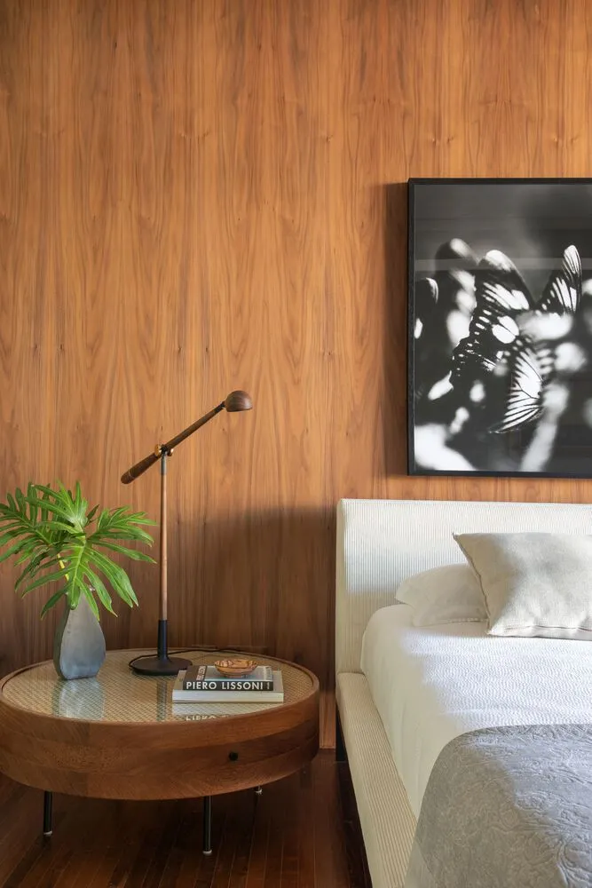 現代簡約臥室,床頭櫃上擺放室內盆栽、閱讀燈、書籍與黑色相框