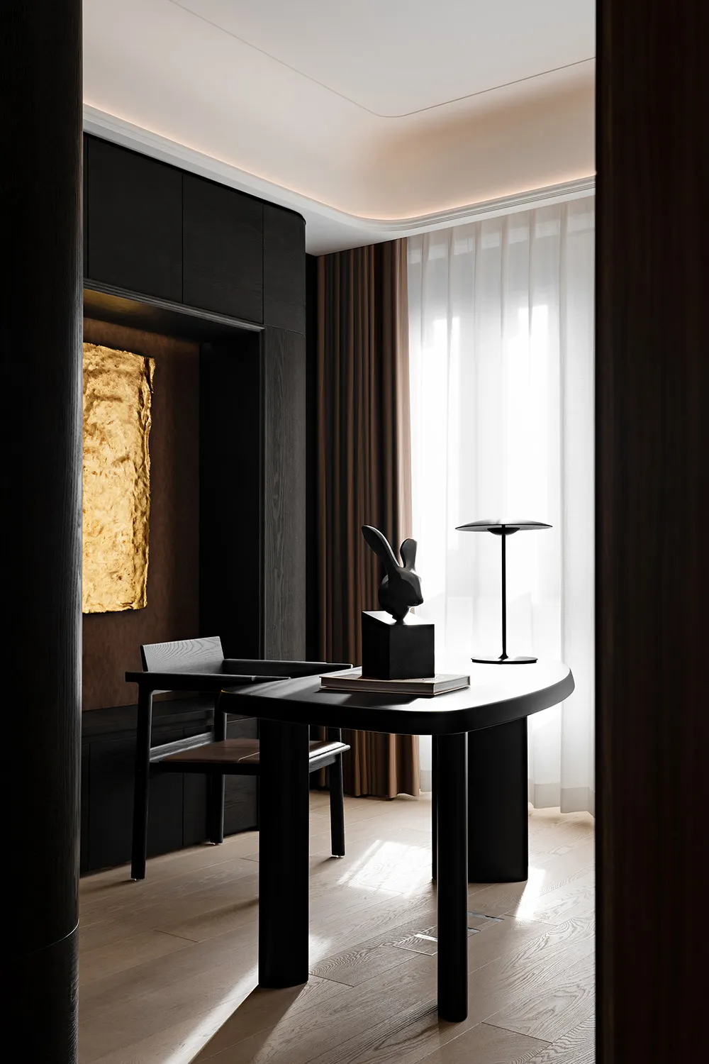 A modern home office featuring a black wooden desk with a rabbit sculpture and a lamp.