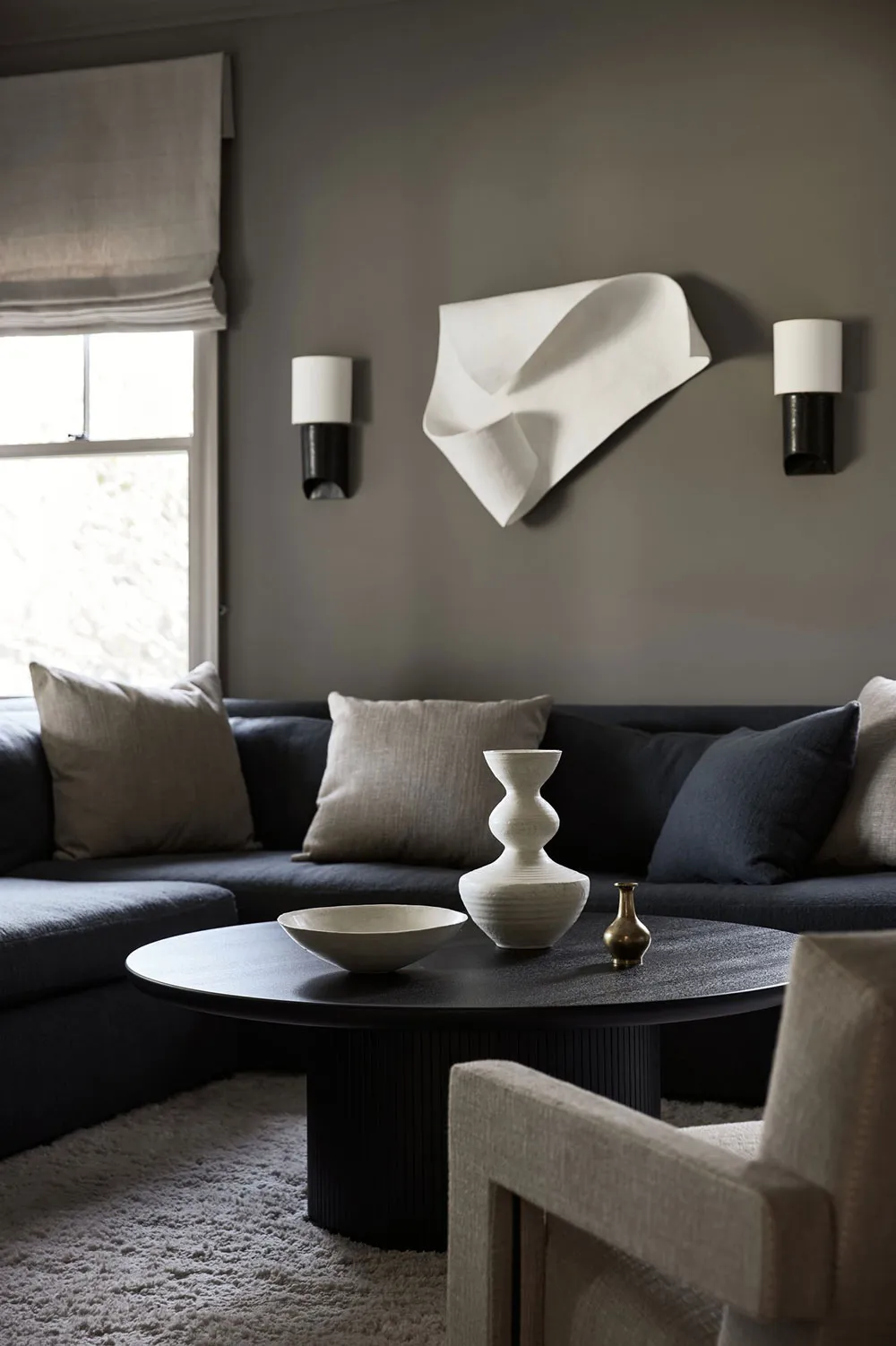 Minimalist living room featuring a textured fabric couch, modern coffee table with decorative vases, and abstract wall art.