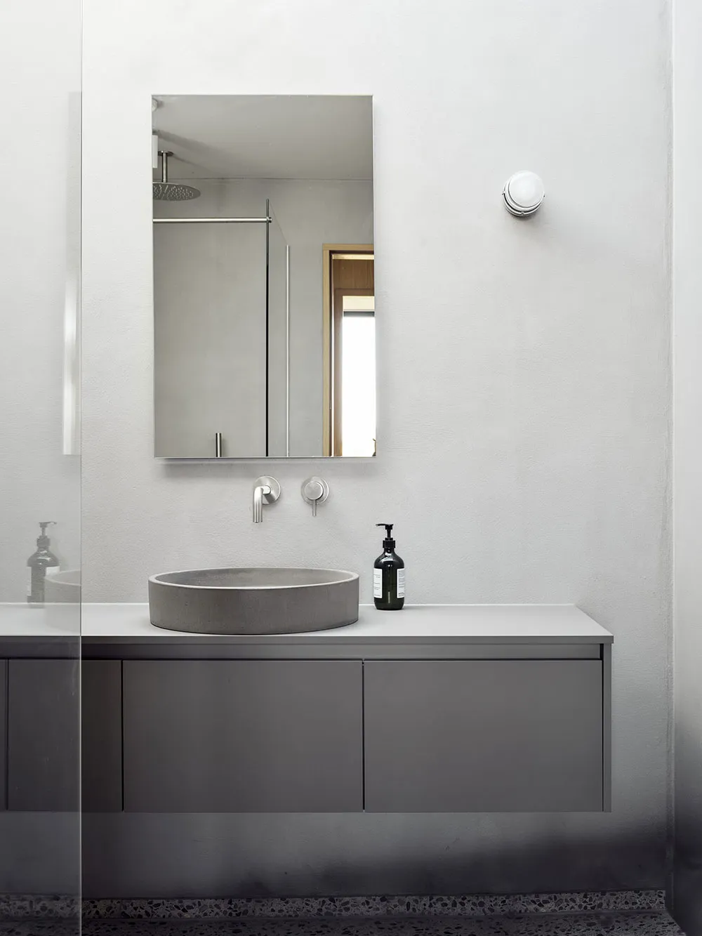Modern bathroom with concrete sink, mirror, and cabinet.
