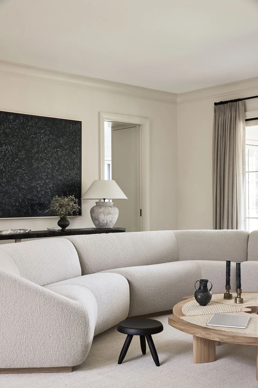 A modern living room featuring a textured fabric sofa, round wooden coffee table, and minimalist decor.