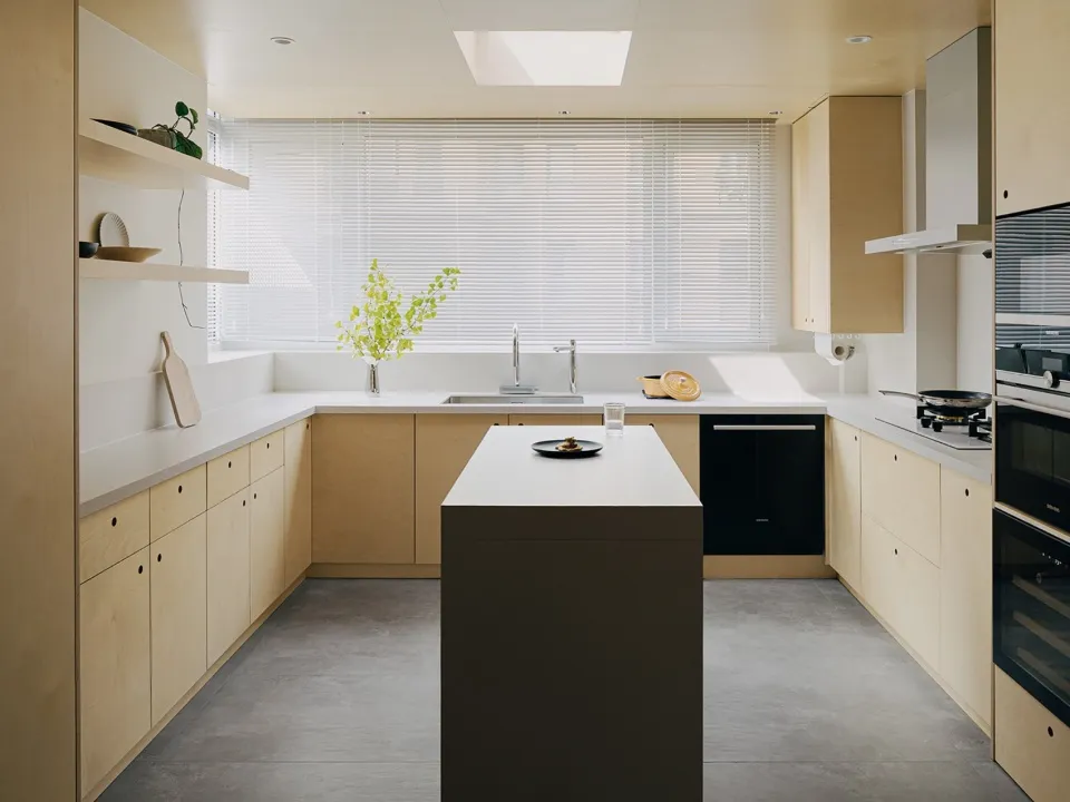 Modern minimalist kitchen with white countertops and wooden cabinetry.