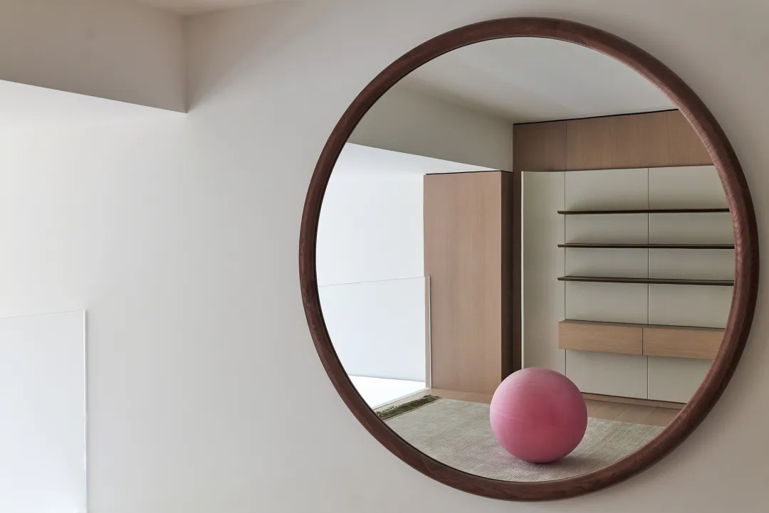 A minimalist room featuring wooden furniture and a pink ball on a rug.