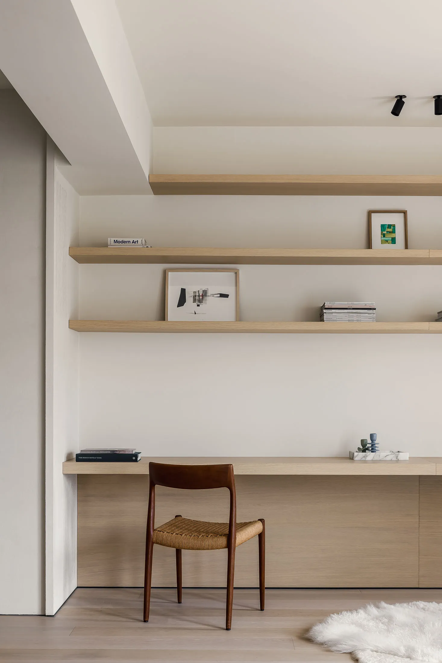 A modern home office with wooden shelves and a woven chair.