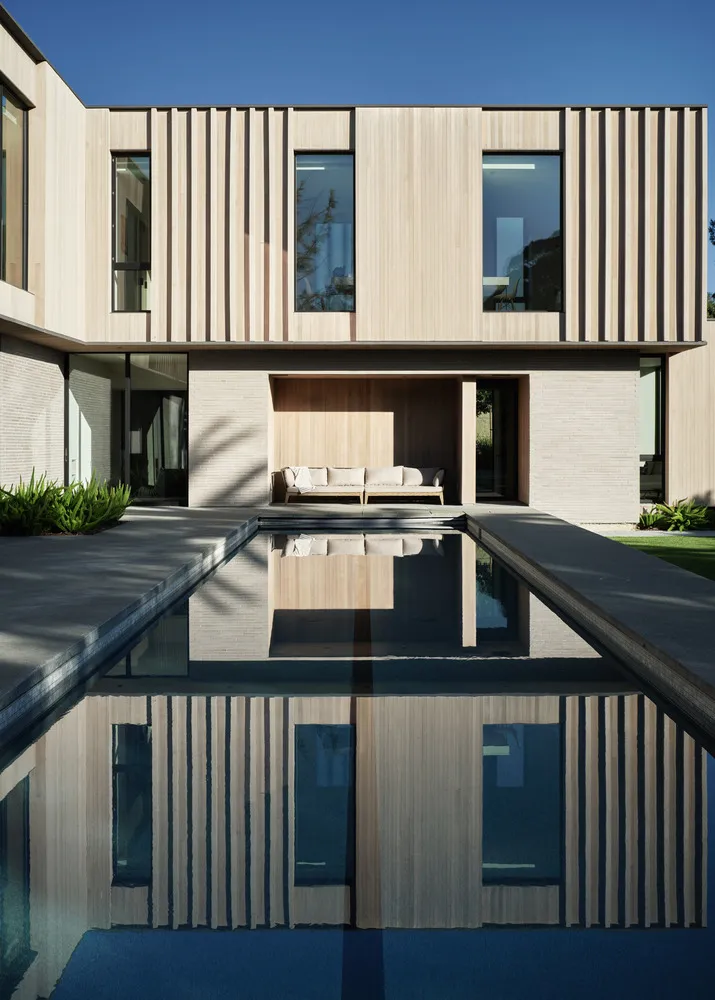 A modern architectural design featuring a wooden exterior reflected in a calm water body.