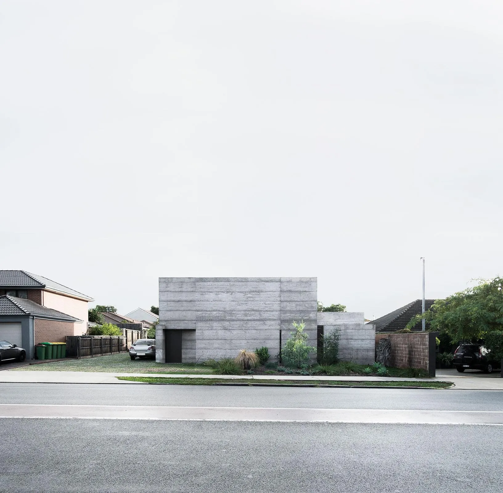 A modern concrete residential house with a minimalist aesthetic, featuring a single-story structure with a flat roof and mini