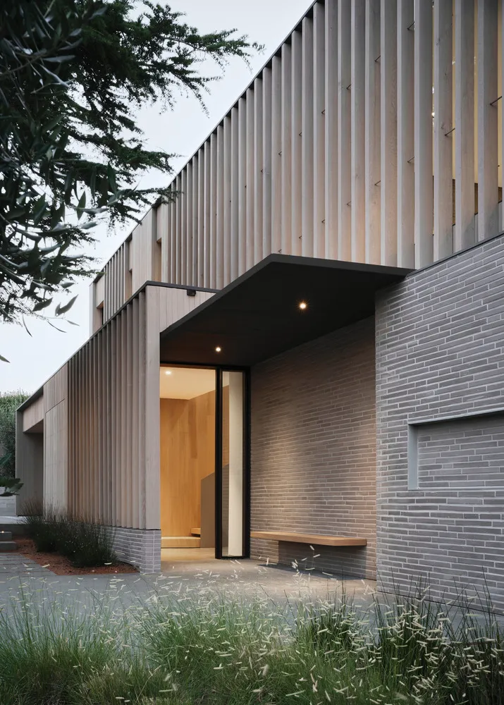 Modern house exterior featuring wooden panels, stone walls, and metal accents.