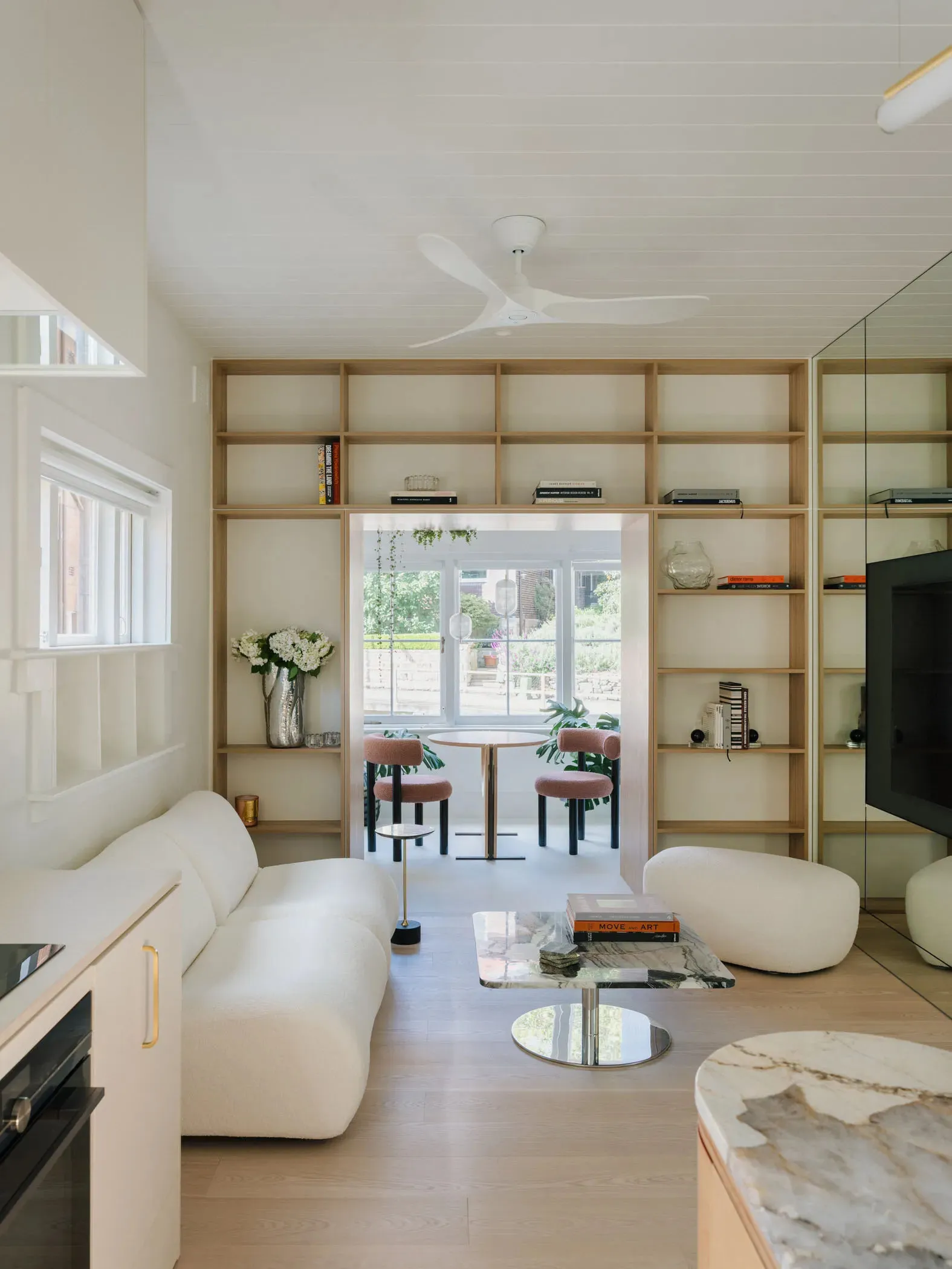 A modern living room featuring wooden shelves, marble coffee table, and cozy fabric seating.