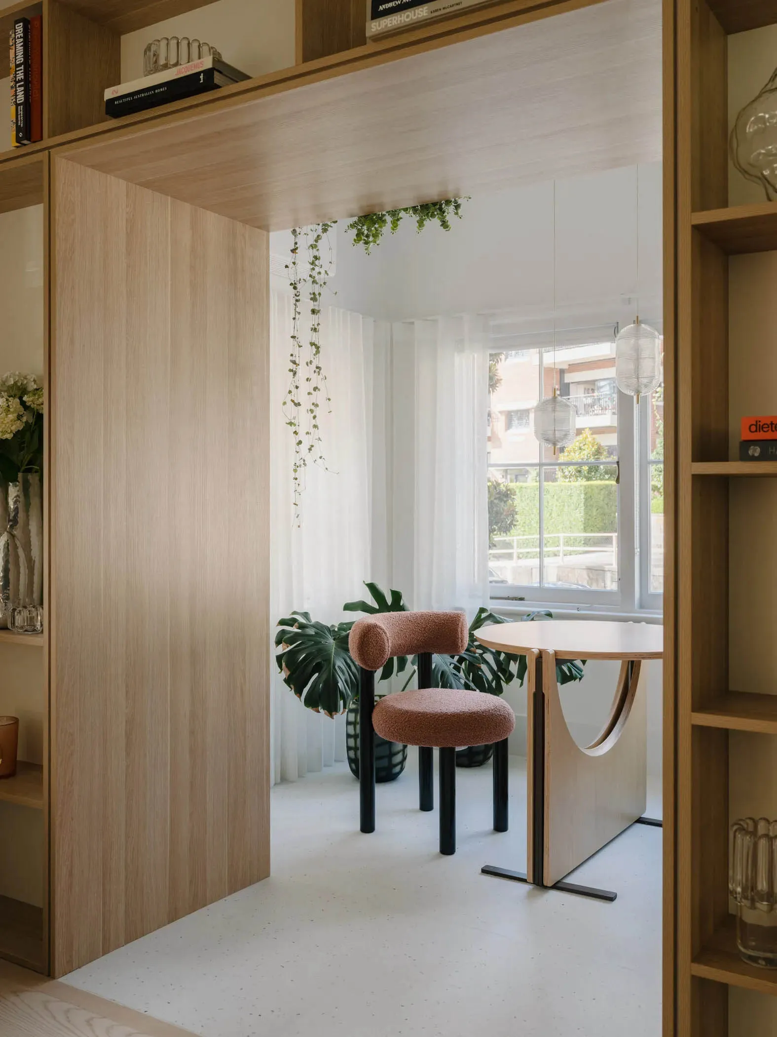 A modern living space with white flooring, wooden furnishings, and glass accents.