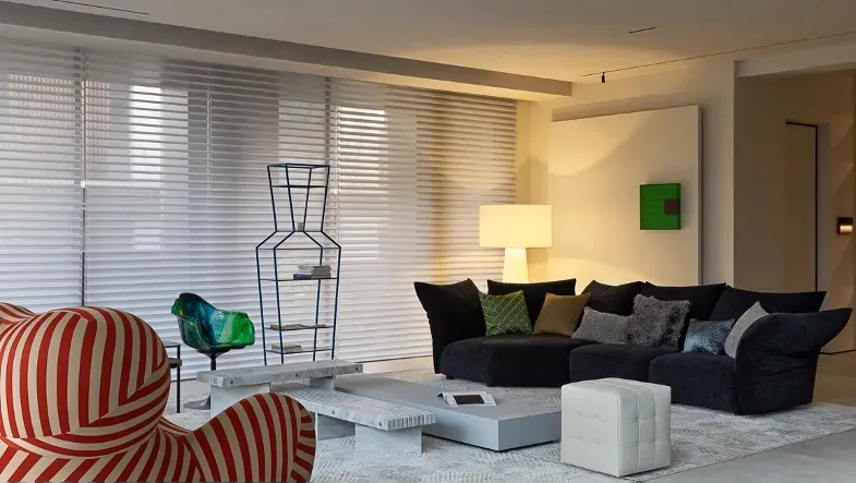 Modern living room with black furniture, fabric upholstered seats, and glass coffee table.