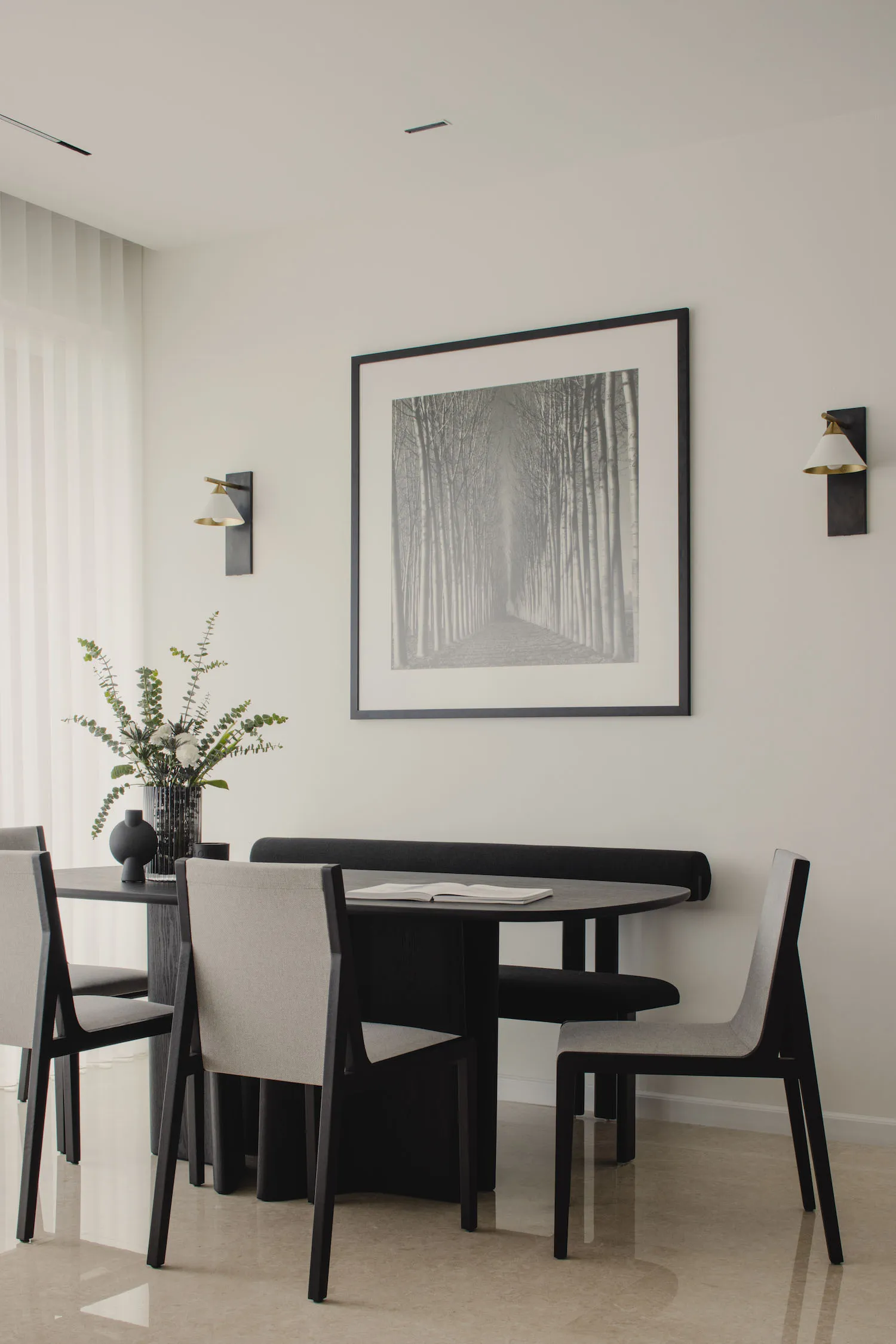 A modern minimalist dining room featuring a wooden table, chairs, and a bench, with a wall-mounted black and white photograph