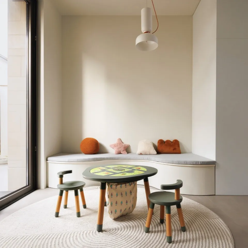 Modern playroom with wooden furniture, including a table and chairs, and a cushioned bench with colorful pillows.