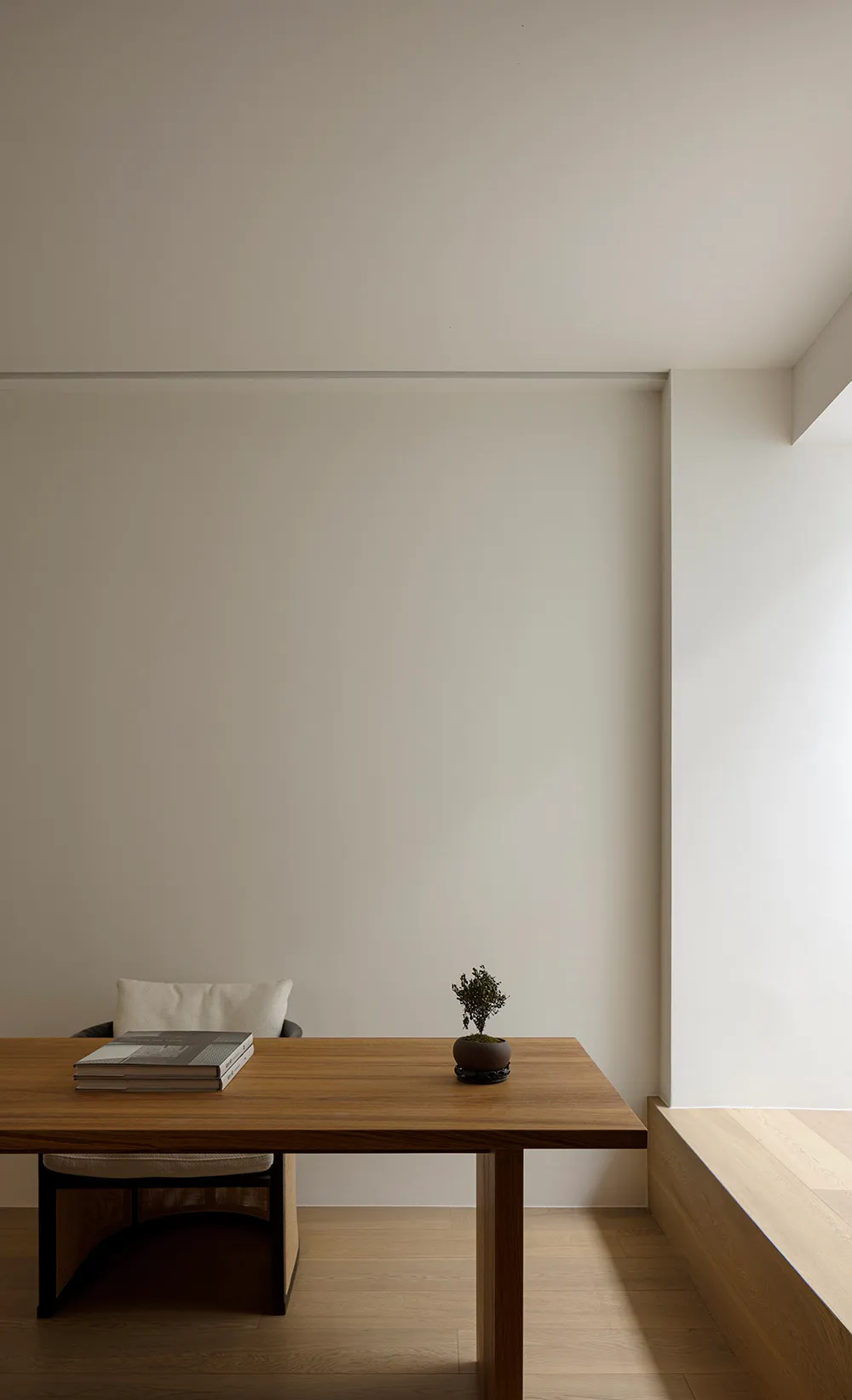 Minimalist home office with wooden desk and chair, minimalist decor, and white walls.