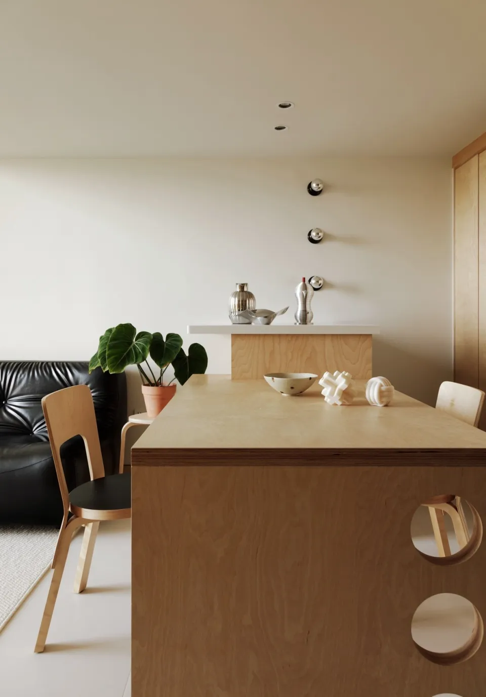 A minimalist kitchen with a wooden countertop and black leather sofa.