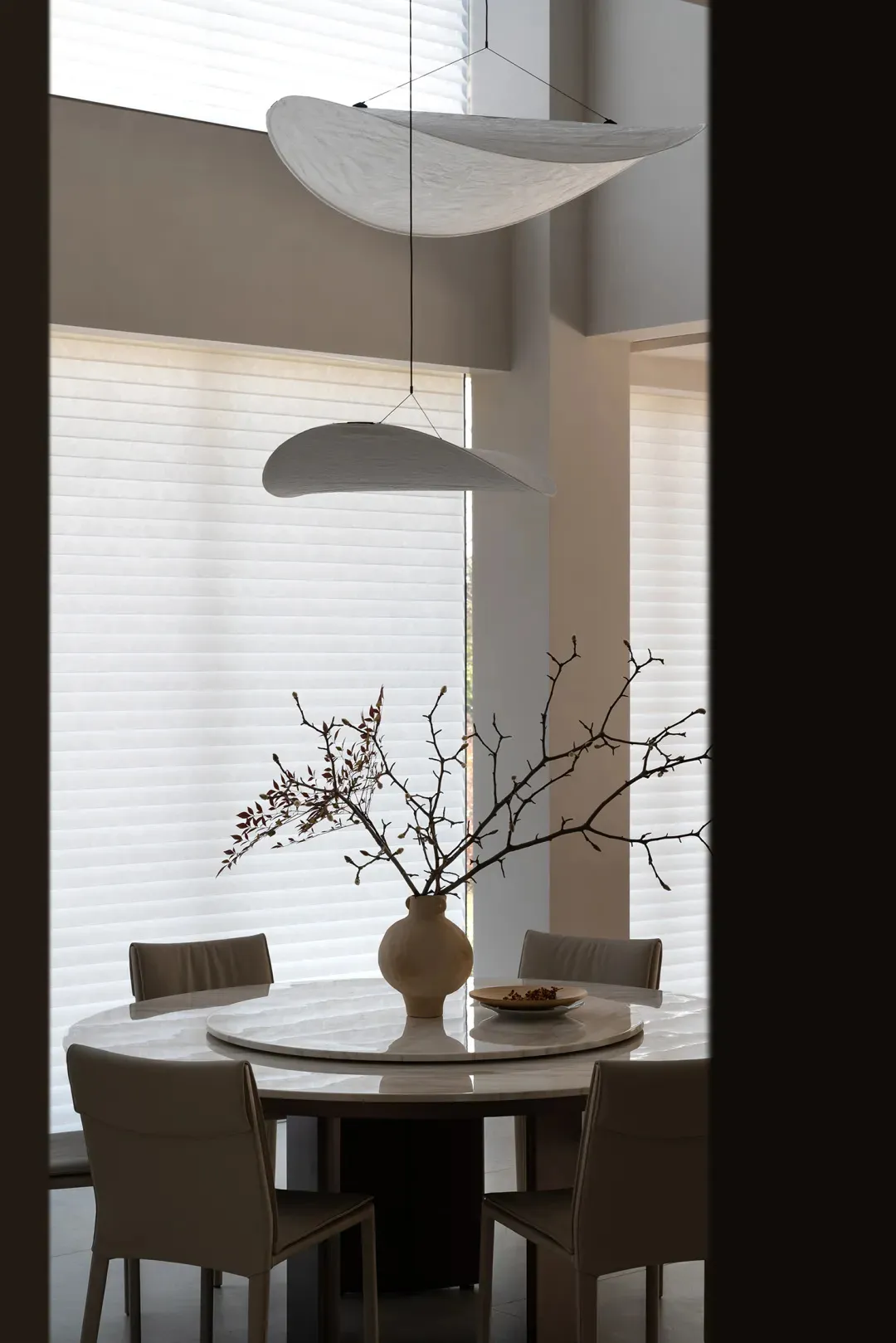 Contemporary dining room featuring modern white marble table and minimalist pendant lights.