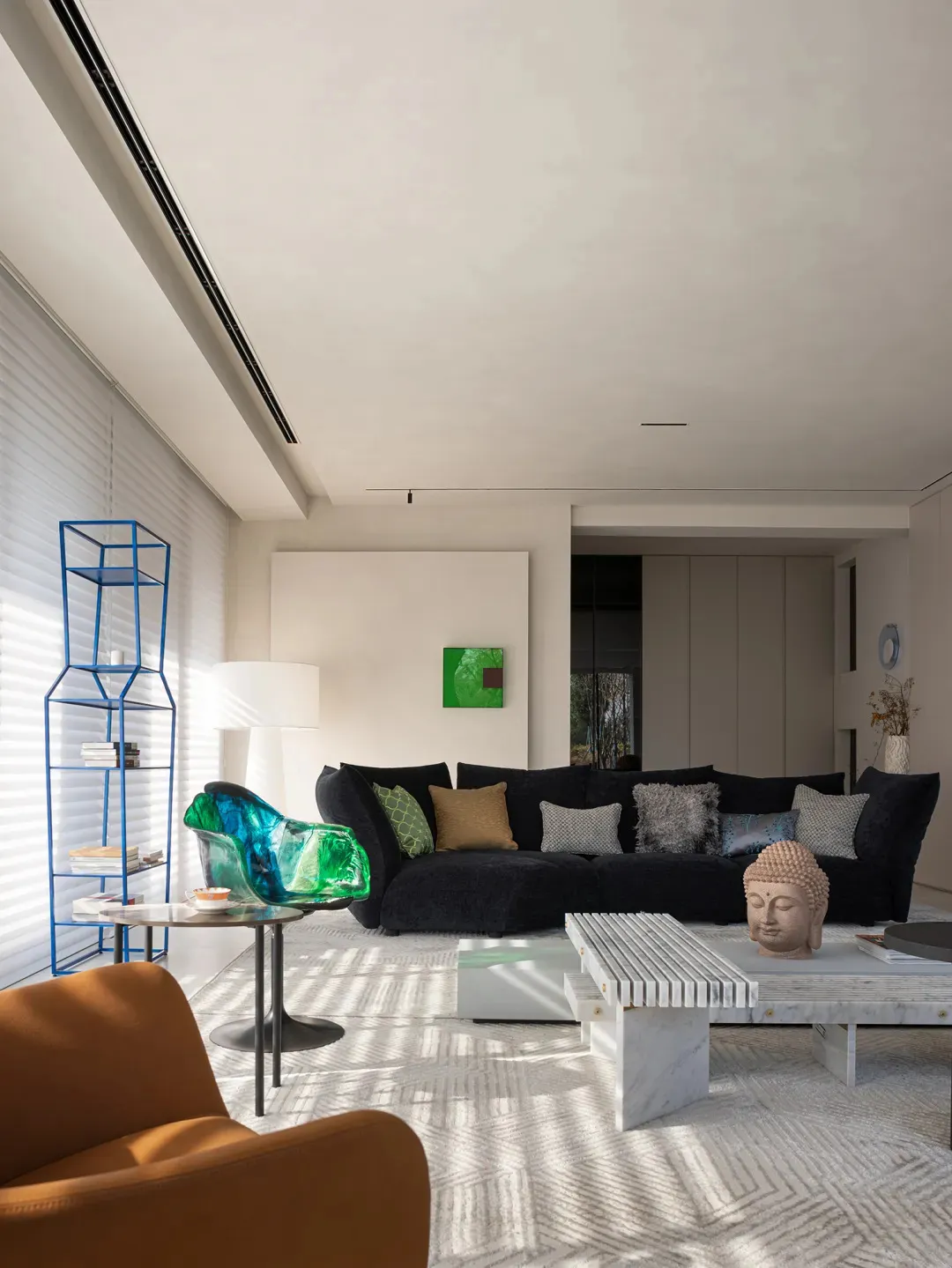 Modern living room with a black sofa, green and brown pillows, and a blue wire shelving unit.