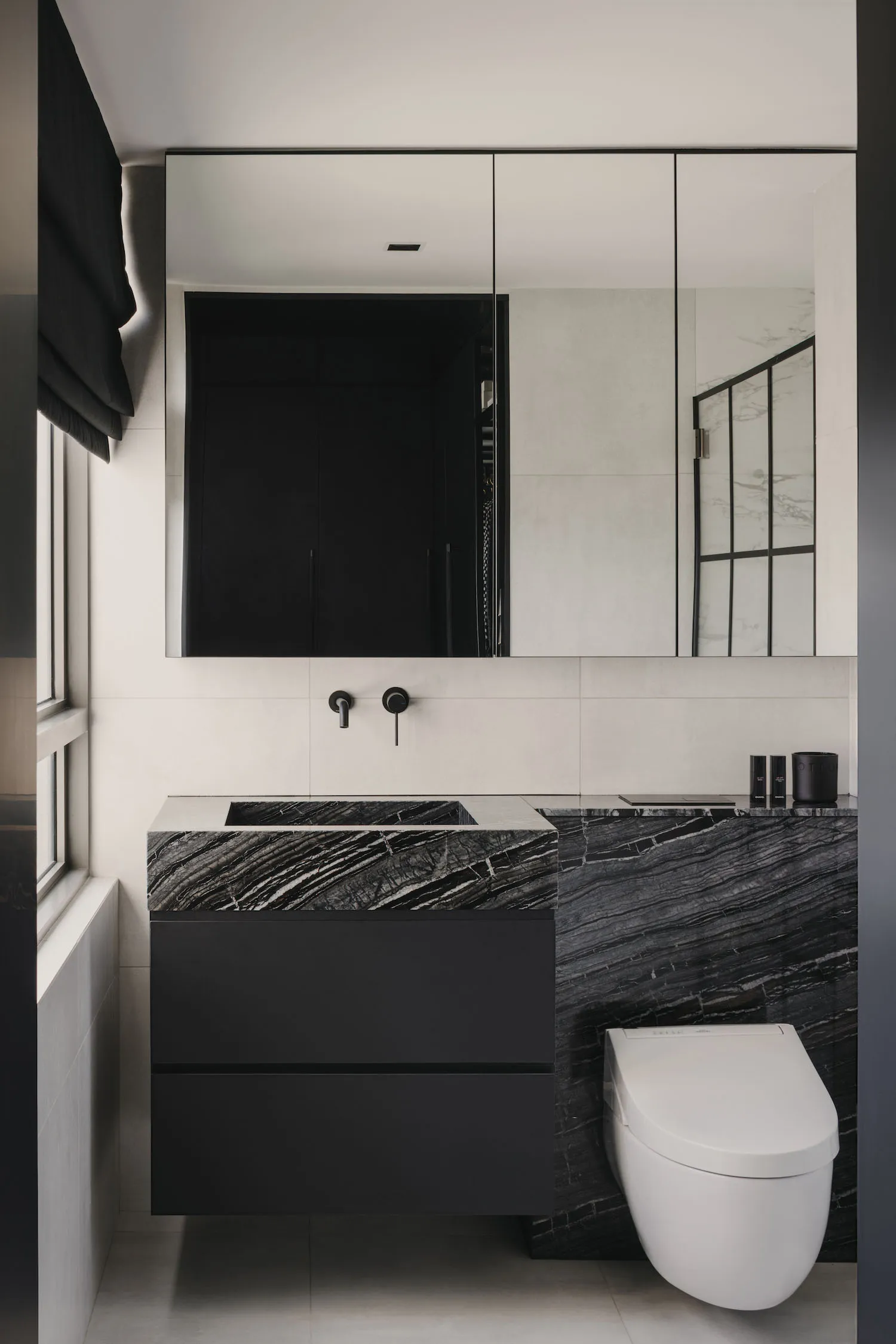 Modern minimalist bathroom featuring black and white marble tiles and a black vanity with a sink.