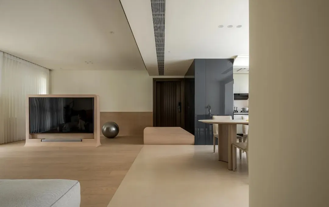 A modern minimalist living room with a wooden floor, white walls, and a television stand.