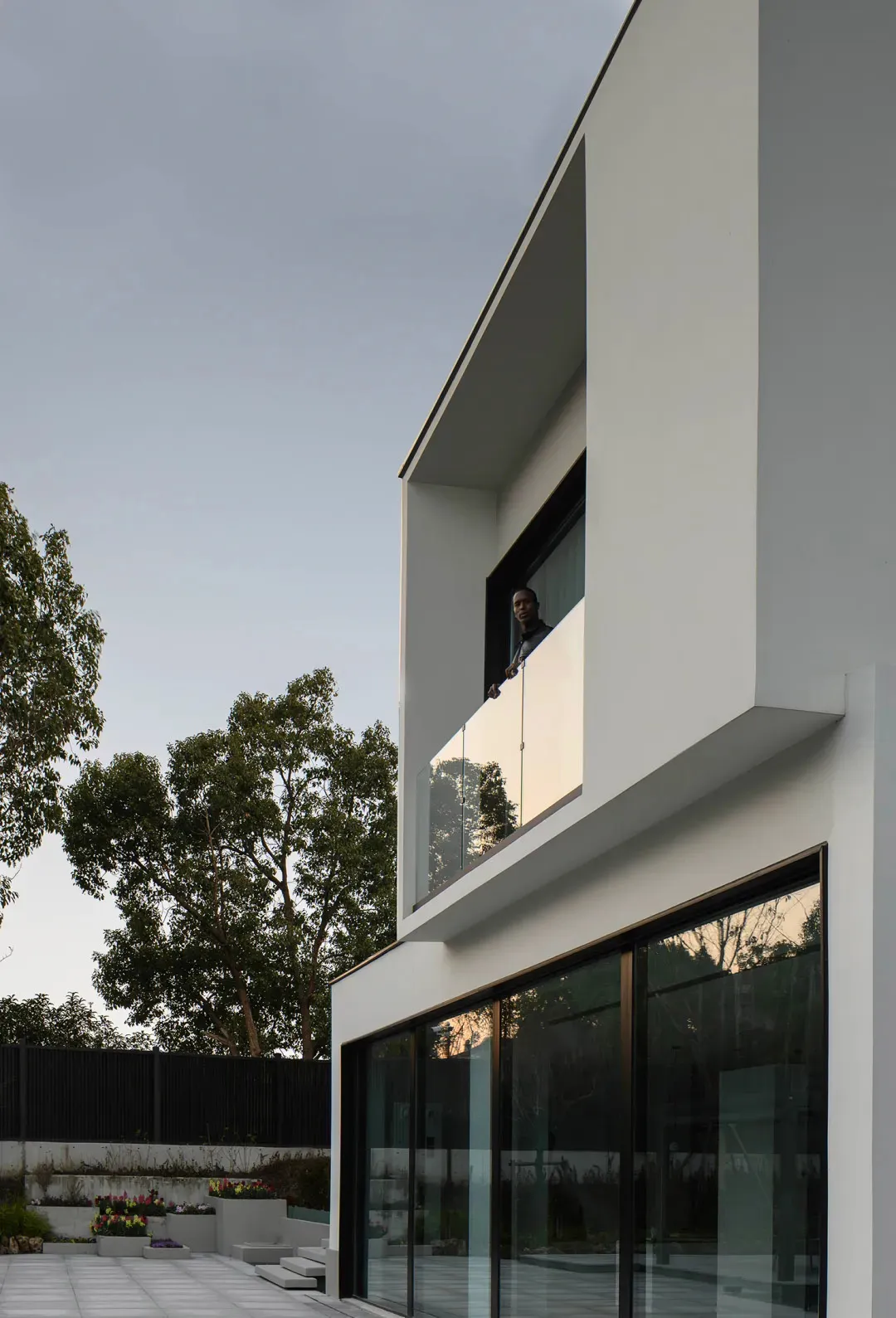 Modern exterior of a house featuring white stucco siding and glass doors.