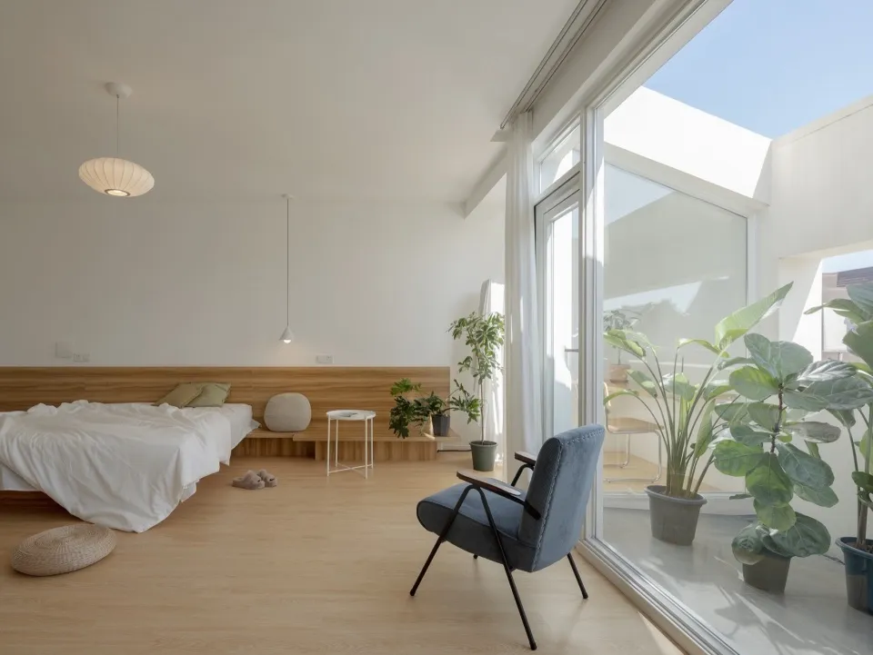 A minimalist modern bedroom featuring a wood floor, white bed, and large window.