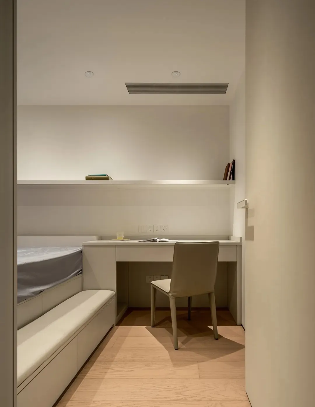 A minimalist bedroom with brown wooden furniture, a white desk, and a bed.