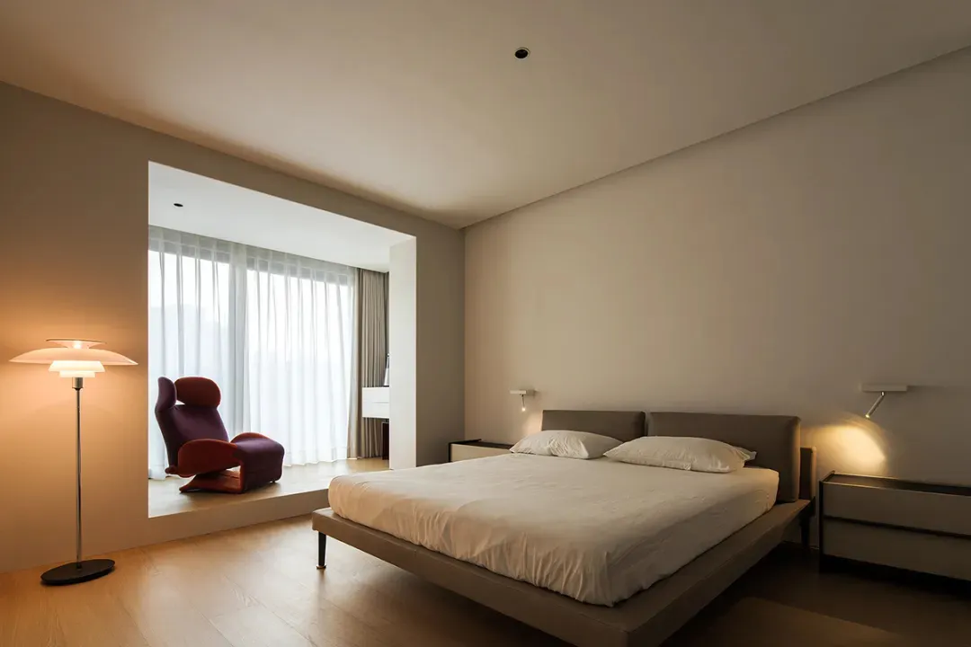 Modern minimalist bedroom with a neutral-toned color palette featuring a white bed.