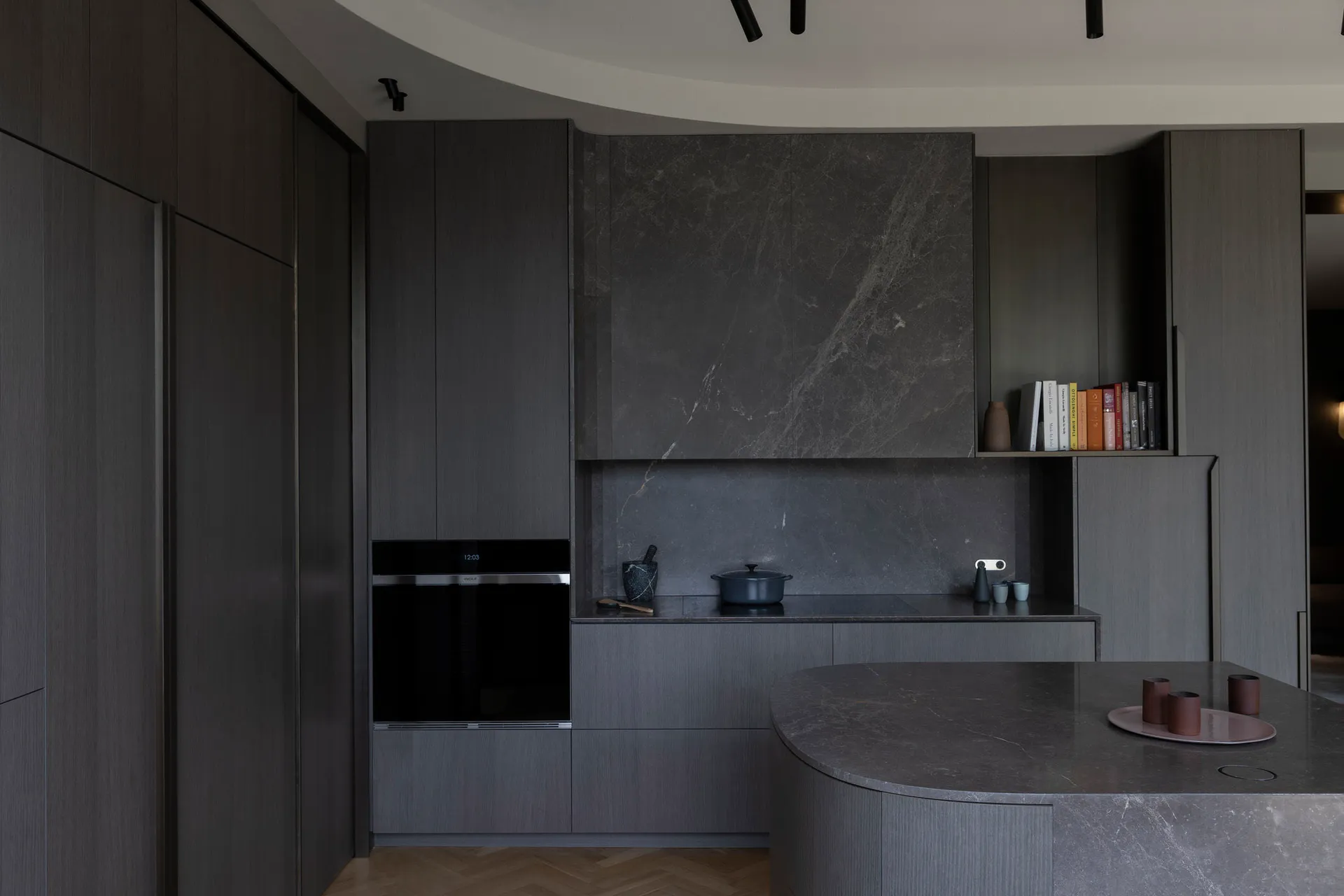 A modern kitchen featuring dark marble countertops and cabinets.
