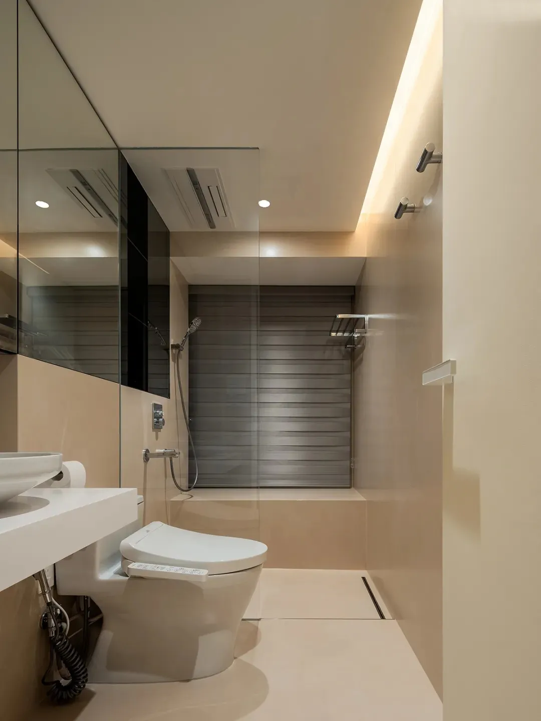 Modern bathroom with white fixtures, beige walls, and a walk-in shower.