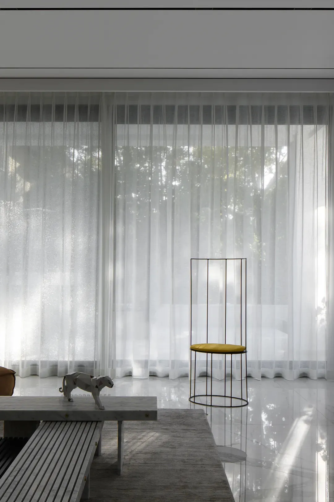 A minimalist living room with glass, marble, and metal elements.