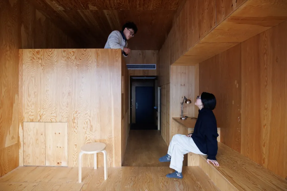 A minimalist living space with wood-paneled walls and floors.