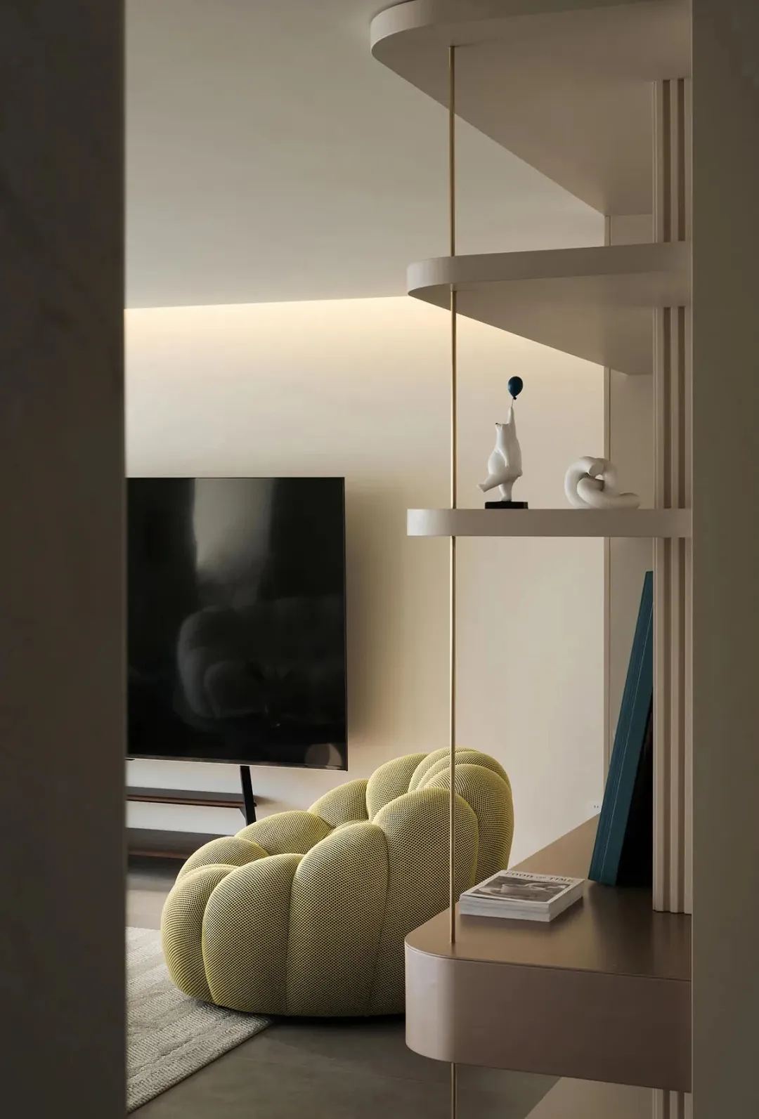 A modern minimalist living room featuring a yellow fabric armchair, a sleek television mounted on the wall, and a contemporar