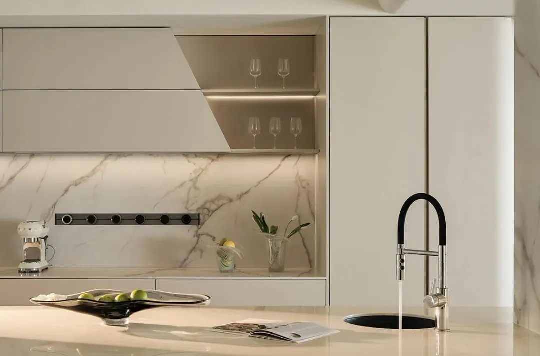 Modern kitchen with marble countertops, white cabinets, and a sink with a black faucet and chrome accents.