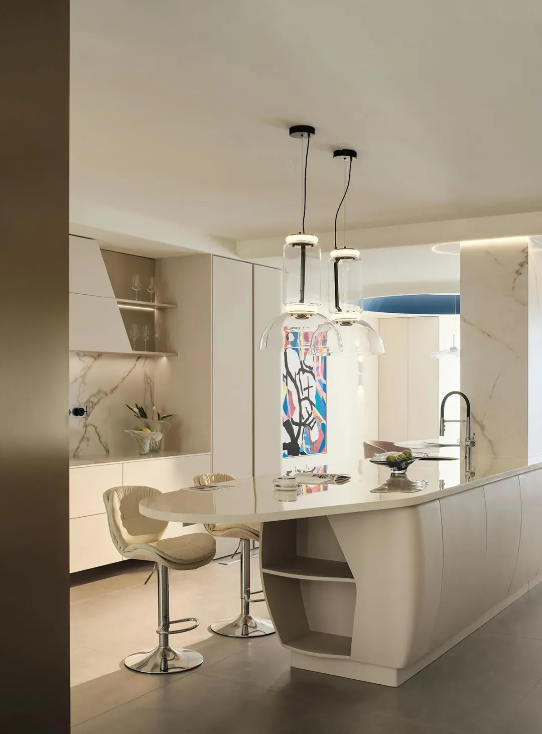 Modern kitchen with white marble countertops and metal stools.