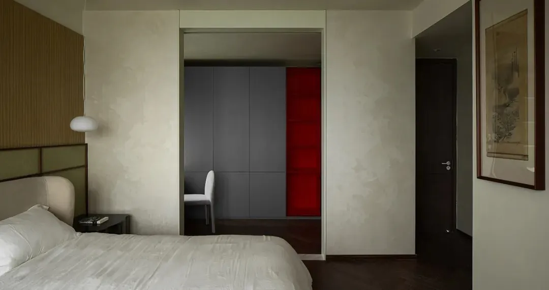 A minimalist bedroom with a white bed, white walls, and white fabric headboard, featuring a wooden floor.