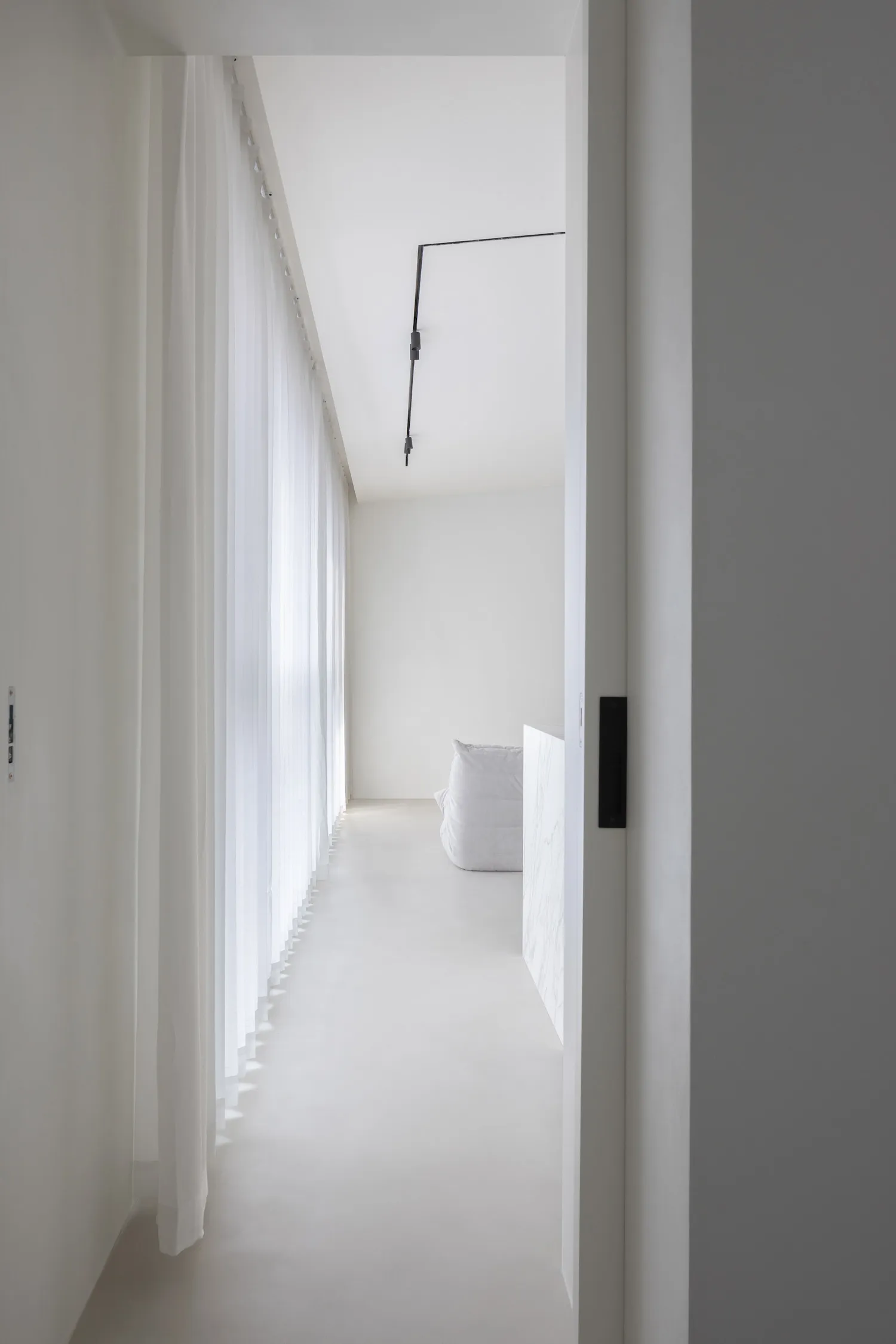A minimalist interior space with white walls, glass walls, and a sleek, modern design.