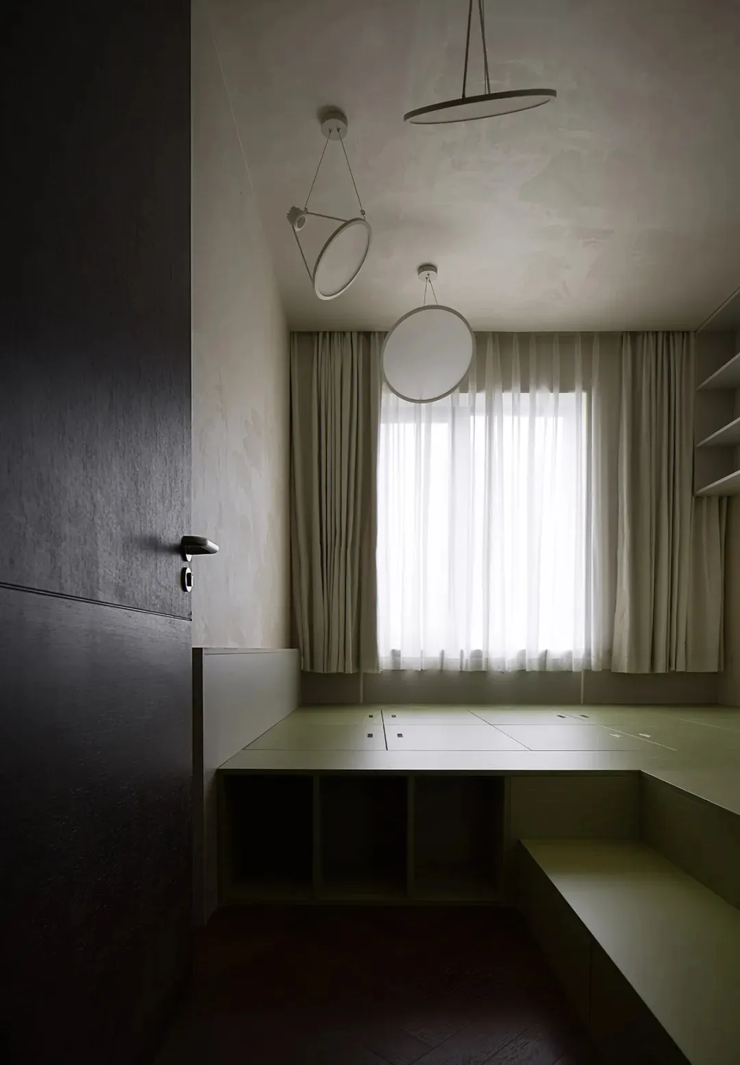 A minimalist modern bedroom featuring green concrete flooring, wooden furniture, and white curtains.