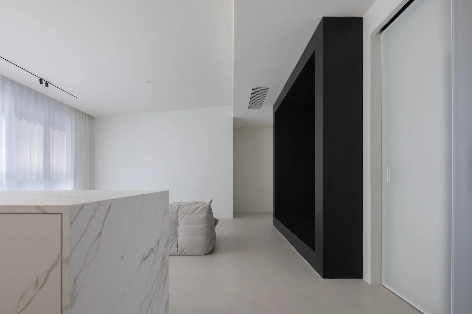 Modern minimalist living room with a white marble countertop and black walls.
